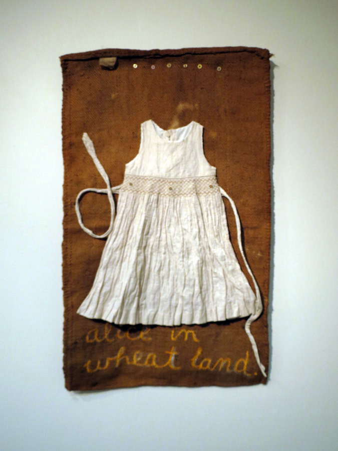  Nalda Searles,  Alice in Wheatland, homage to DH,  original wheat bag circa 1950's, child's hand-smocked dress with embroidery, (sourced from Kellerberrin op shop), hand stitching, oil pastel 