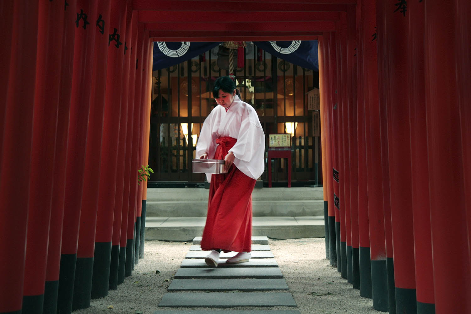  This worker at Kushida Shrine in Fukuoka, Japan, walks under a series of gates carrying a box of donations made to the shrine. Kushida Shrine is famous for a festival in the summer in which participants carry giant floats, some taller than ten meter