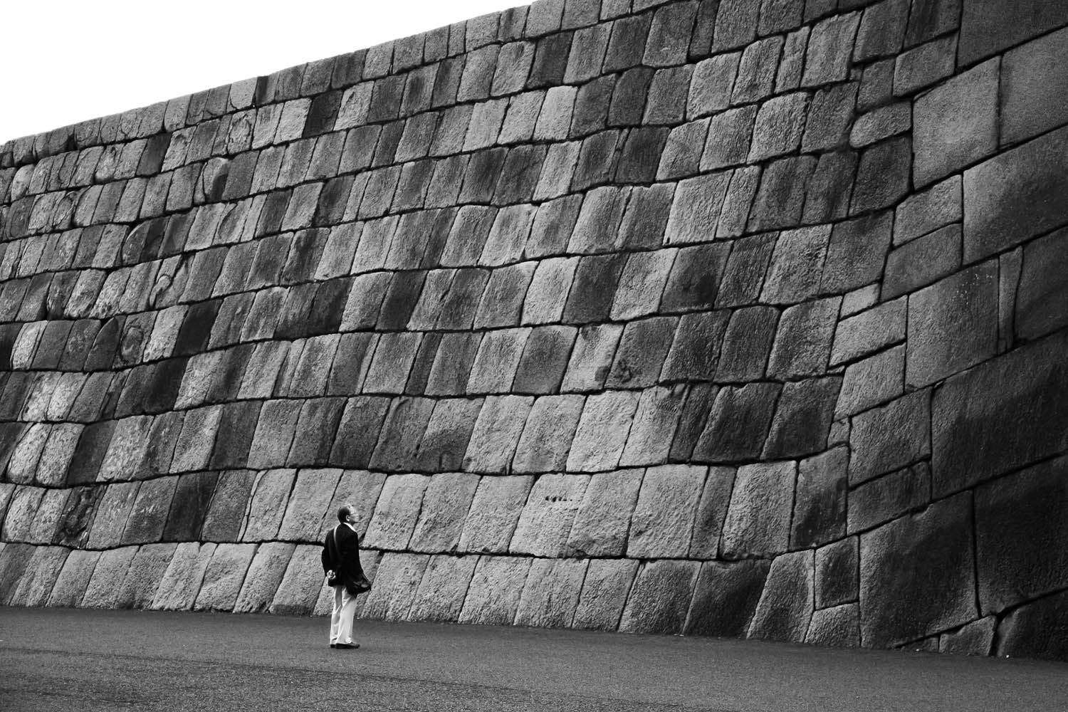 A man inspects the remaining stone base of a castle that once stood in what is now the Imperial Gardens in Tokyo. The castle was completed in 1638, but burned down only 19 years later. This stone base is all that remains.