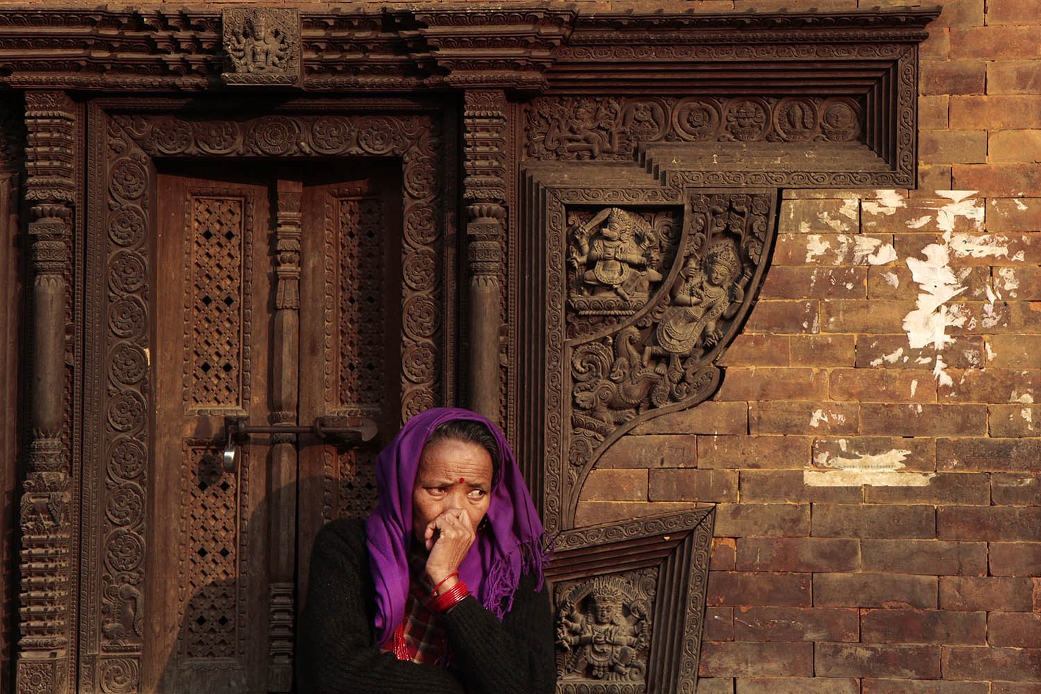 A woman sits near an ancient building in Kathmandu Durbar Square in Nepal. 