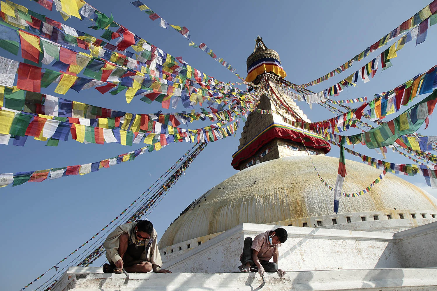 Workers at the Boudhanath in Kathmandu chip paint from the aging facade of the holy Buddhist site. The stupa, one of the largest in the world, had accumulated many layers of paint over its existence.