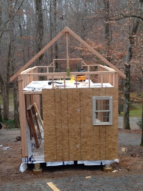 Sheathing going over the main entrance. This pic also shows the jig I made to support the 16 foot ridge beam. Putting it up yourself requires a little help from scrap lumber. 