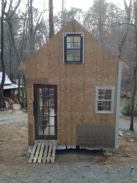 Sheathing completed. Temporarily put up a trim board on the left side and some samples of the concrete shingle siding. It's not cheap stuff, but I've got a good source for it, and it is very durable...and heavy! 100sq. ft. weighs over half a ton! 