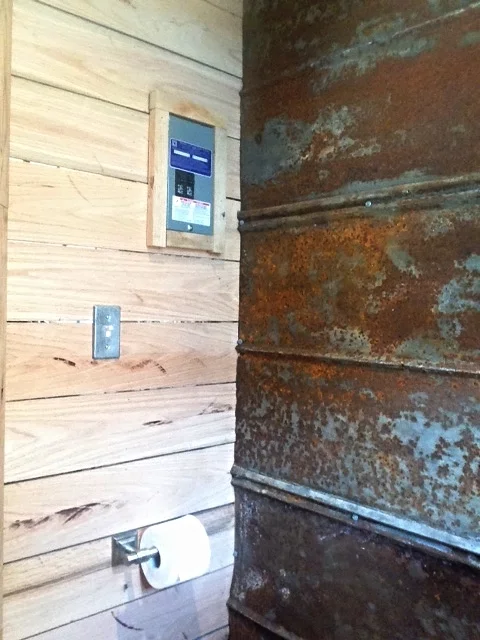 Toilet paper holder, lightswitch, and electrical control panel on the opposite wall. 