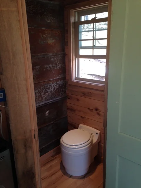 The tin wall to the left will eventually have a door to an outside shower. Since the toilet is not permanently in place, it can be moved against the other wall.