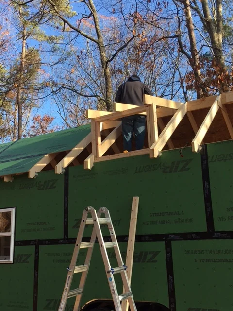 Keller fastening aluminum straps over the ridge beam to tie the rafters together.