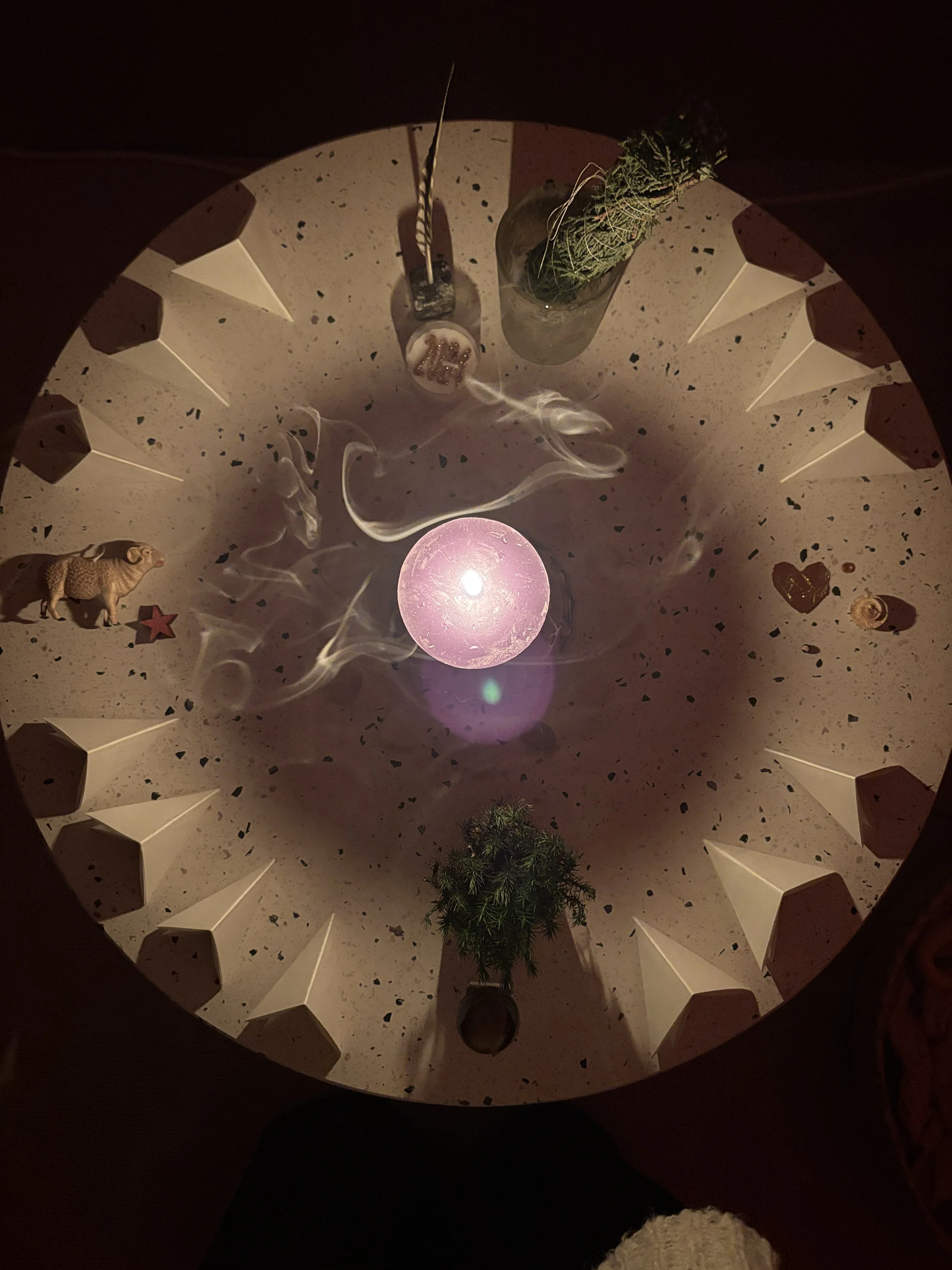 Ceiling view of a decorative space with a pink orb light at the center, surrounded by small trees, animal figurines, and various objects, with a circular arrangement of white cone-shaped structures around the perimeter.