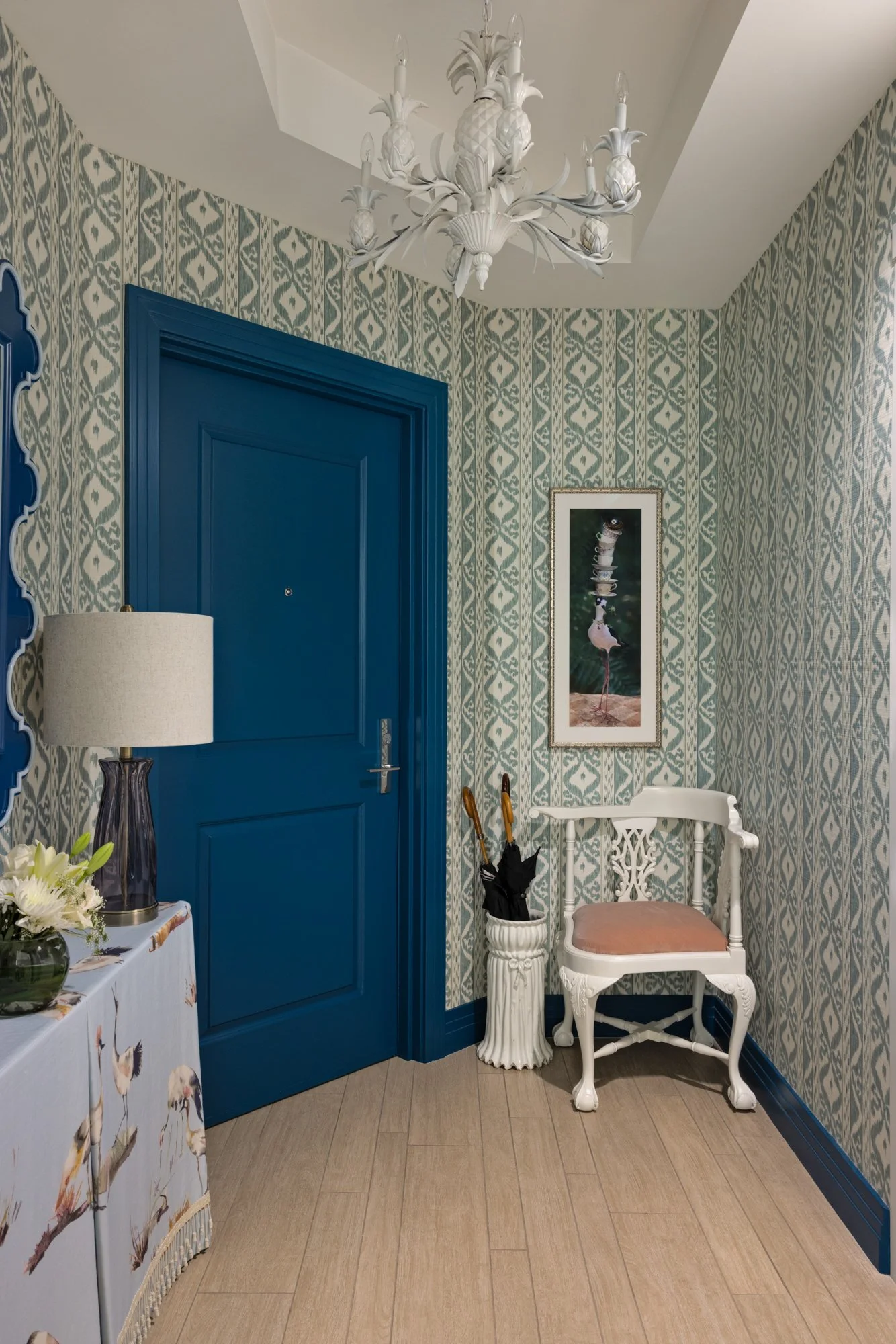 Coastal condo entry with patterned wallpaper, blue door and decorative console