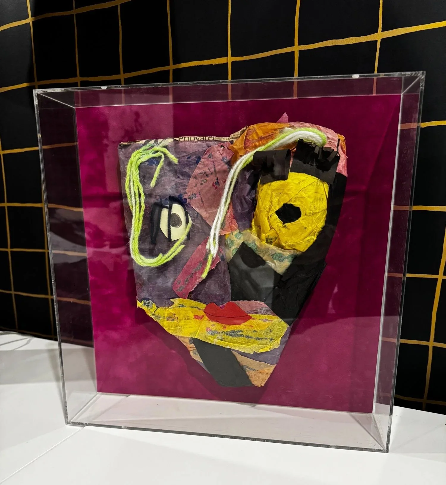 A colorful, Picasso-inspired child's art mask displayed in a clear acrylic shadow box