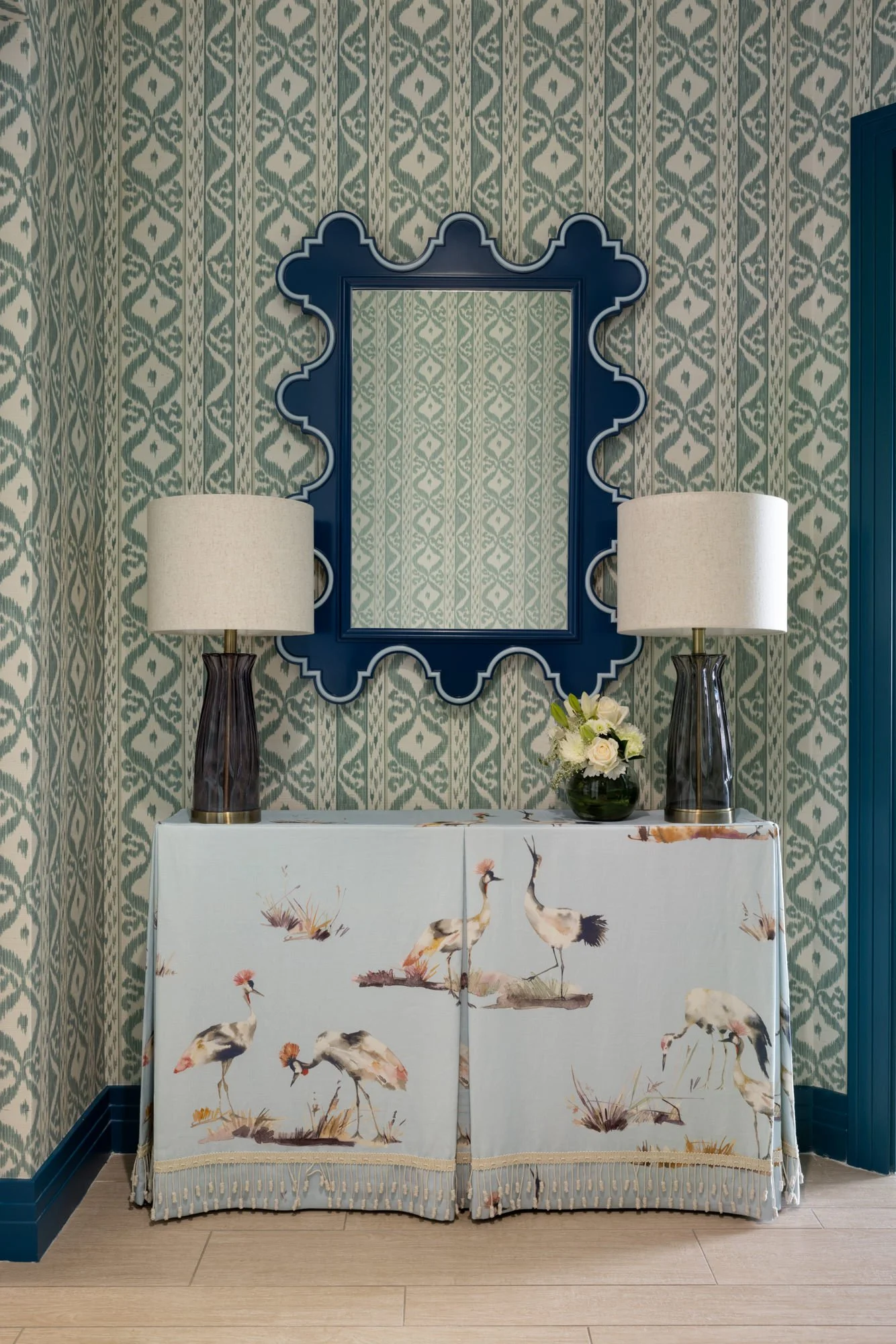 Coastal condo entry with patterned wallpaper, blue mirror and crane fabric console
