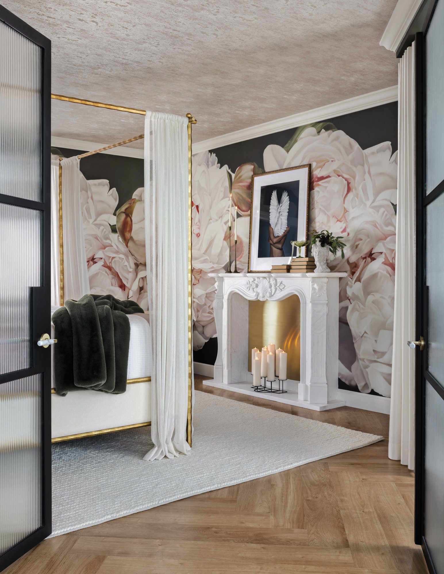 Primary bedroom with oversized floral wallpaper, canopy bed and fireplace