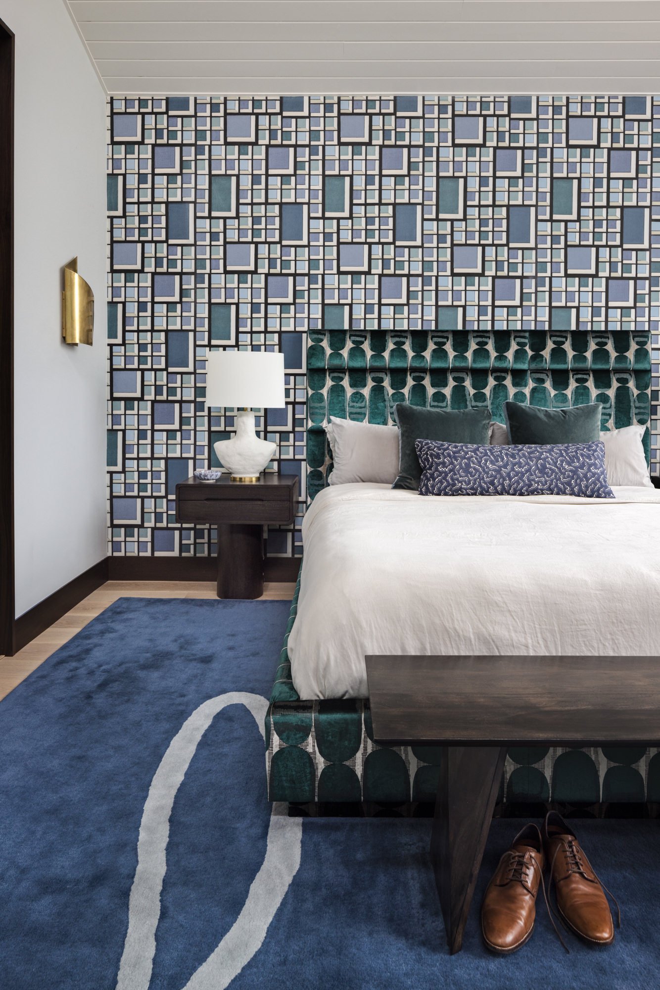 Primary bedroom with geometric blue wallpaper, upholstered bed and blue area rug