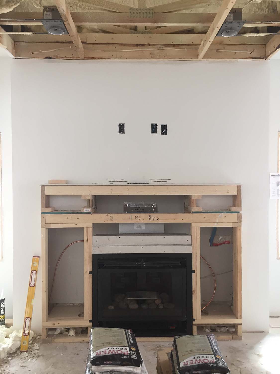 We had to make a last-minute design change when we found that the fireplace required 10" more headroom to provide a safe separation to combustibles. Where the fireplace was to be 6" above the floor and with a lower mantel, it's now down at floor level and the mantel has been raised up. Who knows? Maybe it will look better this way.