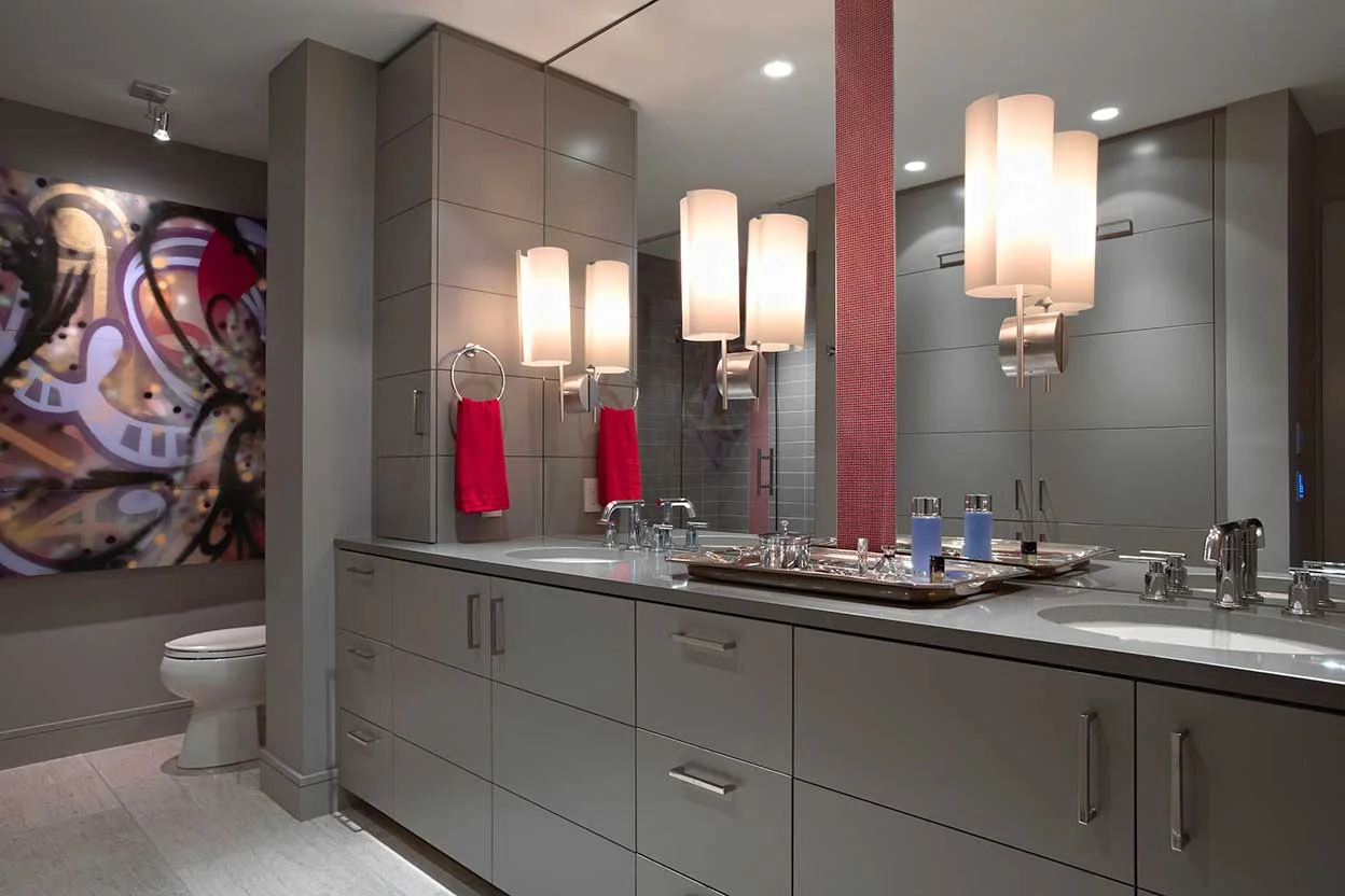 The warm grey base tone is punctuated by strips of micro-mosaic tiles, all amplified with a full width mirror