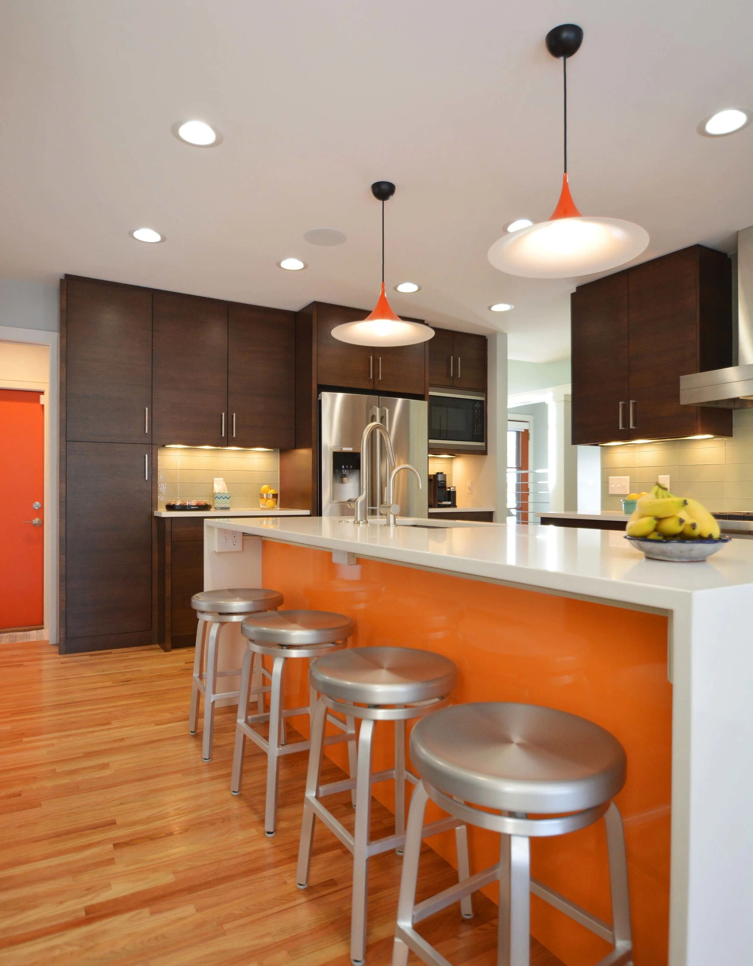  Bold red-orange accents are a counterpoint to the deep wood tones and cool green glass tiles in the kitchen.  Cabinetry: Steven Cabinets 