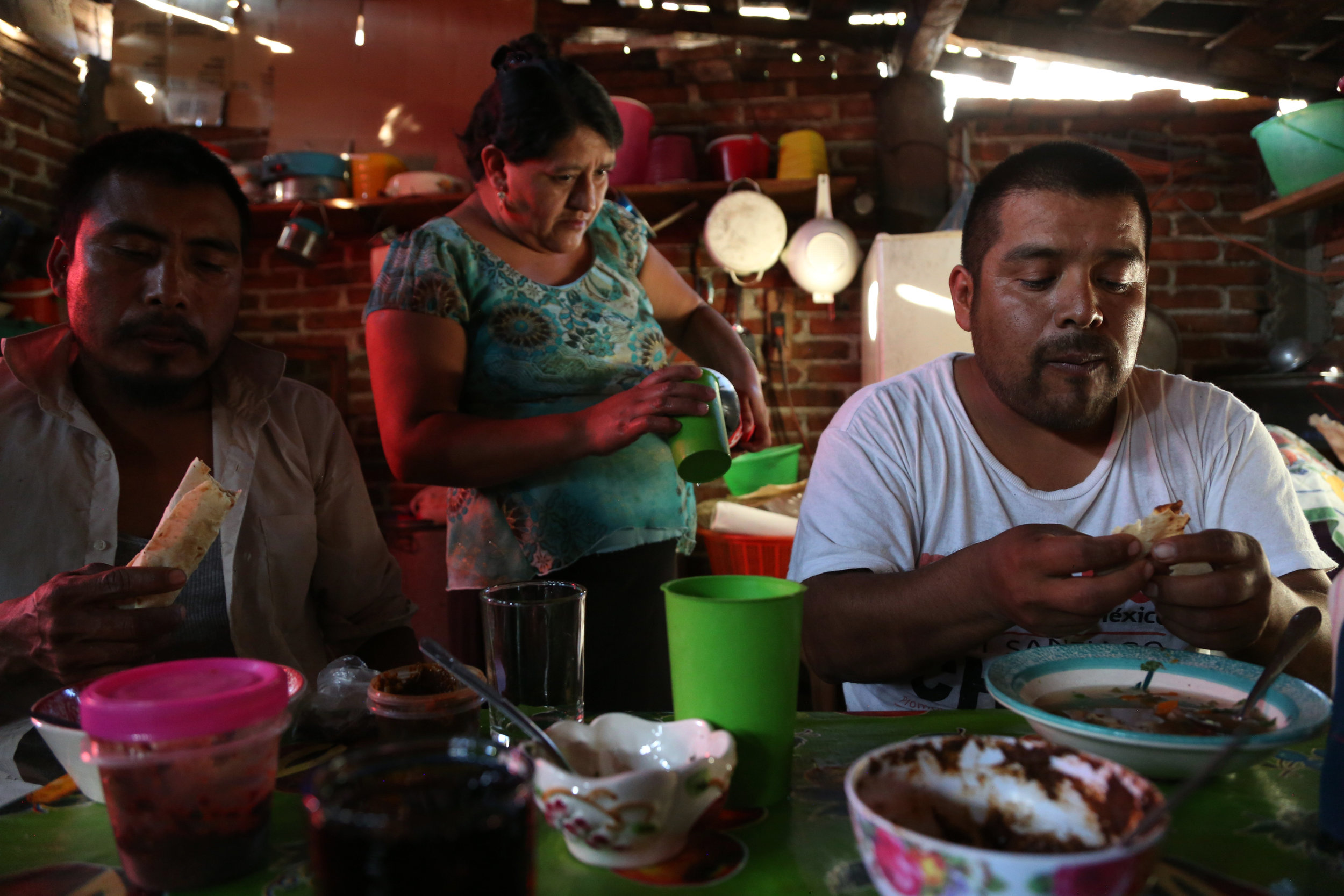  Fortunato Angeles and his brother-in-law, Raul Marin, eat pozole and fresh tortillas after a day at the palenque in  San Juan del Rio, Oaxaca.  