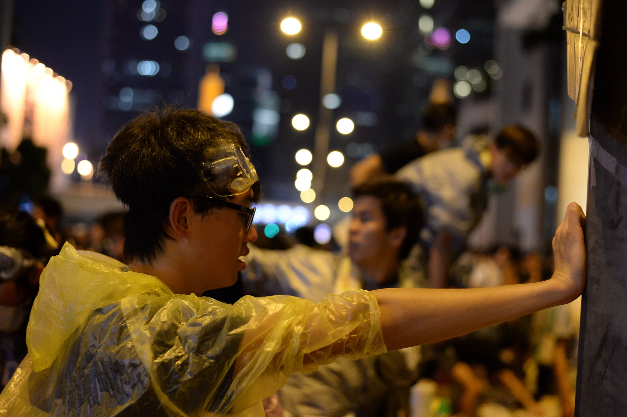 A student occupier in protective gear rests momentarily against a road barrier in Admiralty.