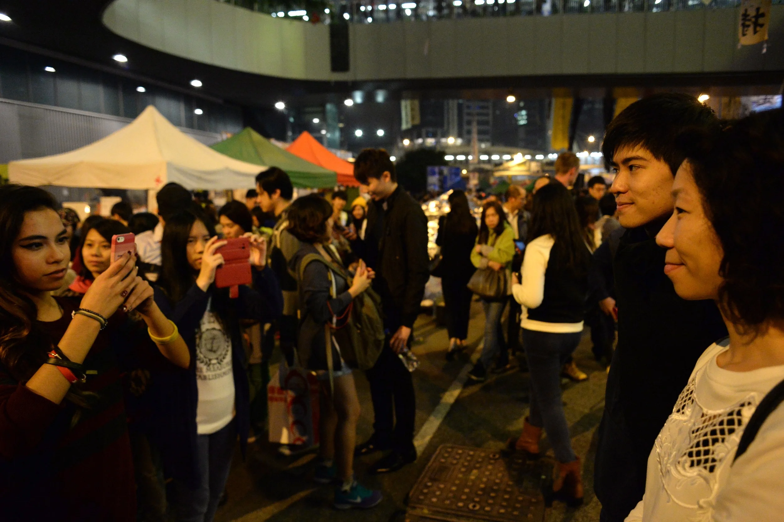 As eviction loomed, the final nights of the occupy site at Admiralty were characterized by an atmosphere by turns reflective, optimistic, frustrated and, on the final night, almost festive. Here, Lester Shum, one of the most recognizable student leaders from HKFS, poses for pictures with admirers.