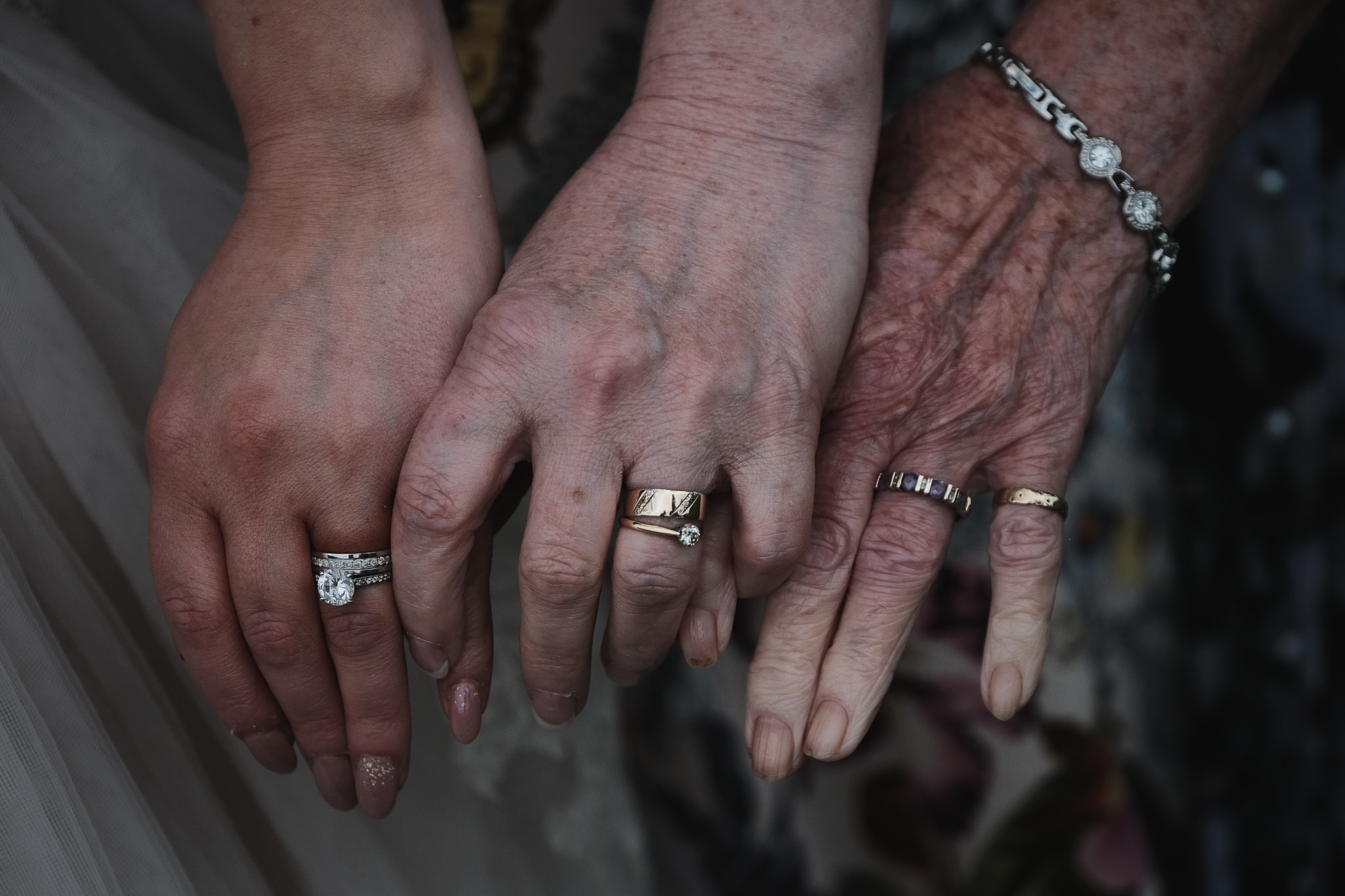 The bride, her mother and her grandmother show off three generations of wedding rings at Newton Hall, Northumberland by Barry Forshaw