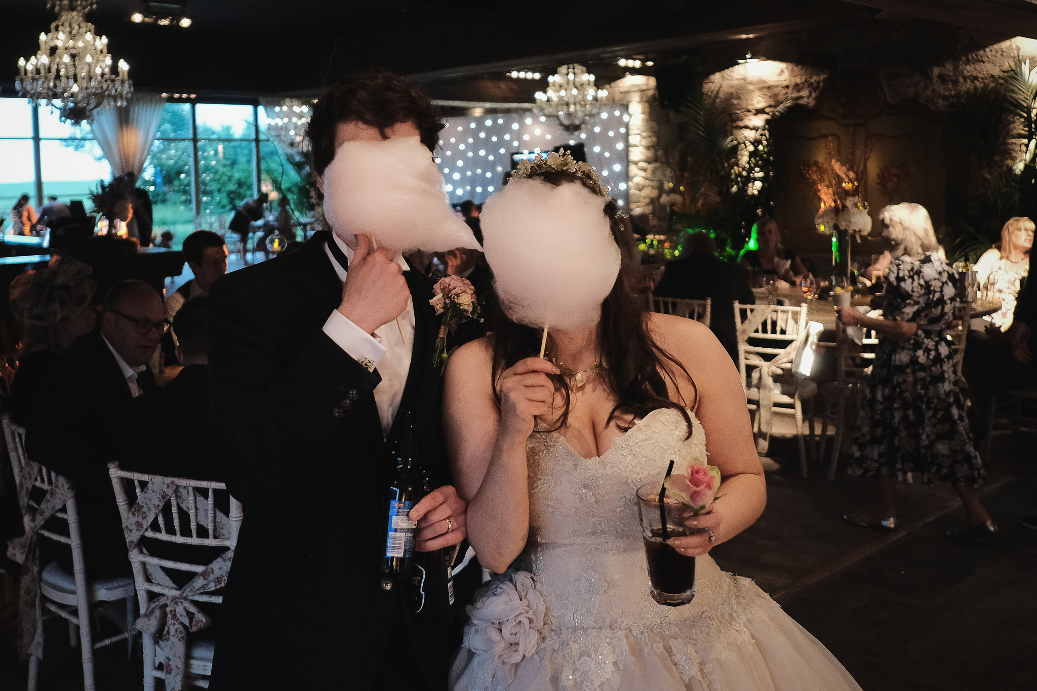 The bride and groom hide behind candy floss at Newton Hall, Northumberland by Barry Forshaw