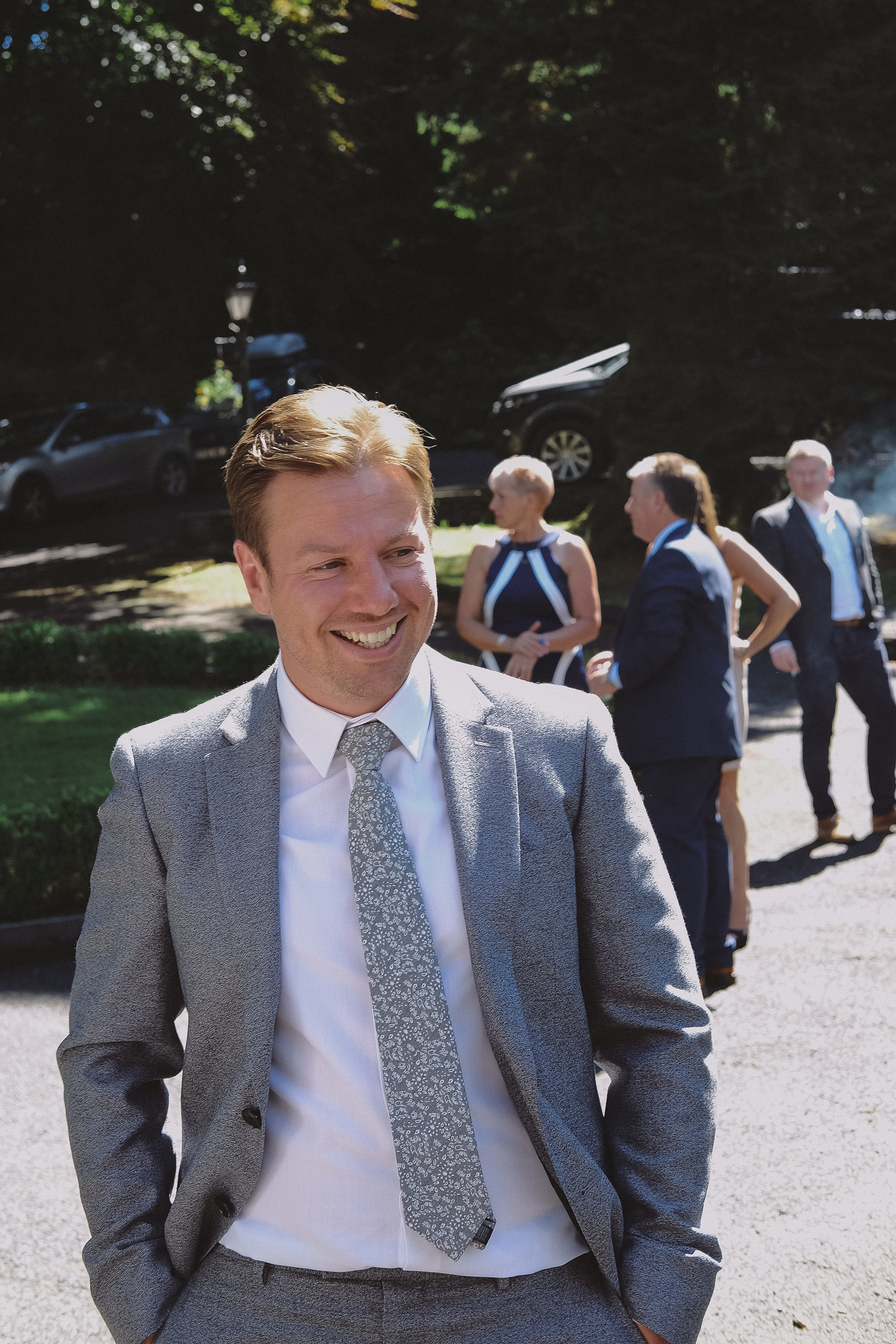 The groom smiles with his guests before his wedding ceremony at Julia and Daren's Lake District wedding by Barry Forshaw