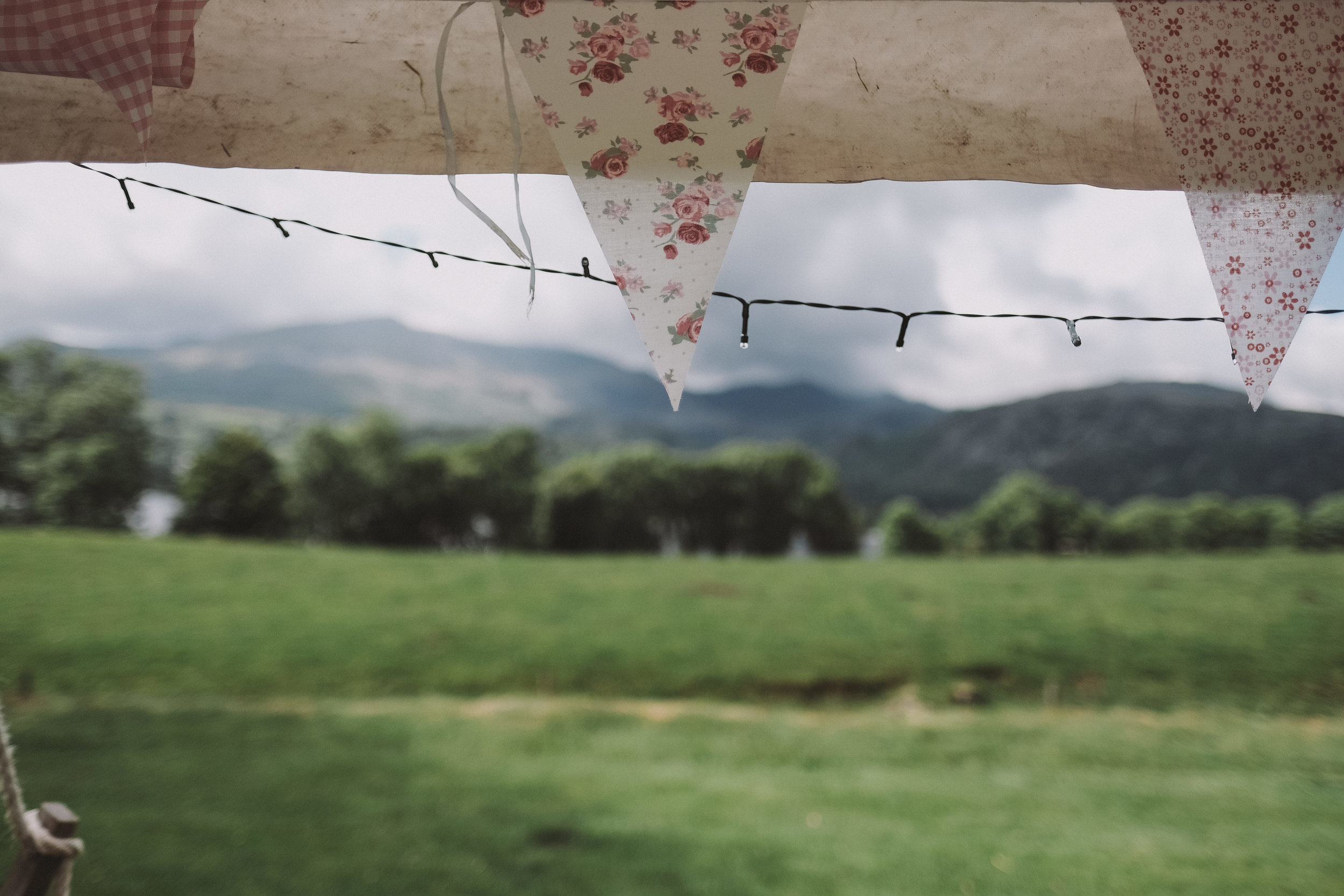 Bunting in the marquee with the hills over Coniston water out of focus in the background at Julia and Darren's Lake District wedding by Barry Forshaw