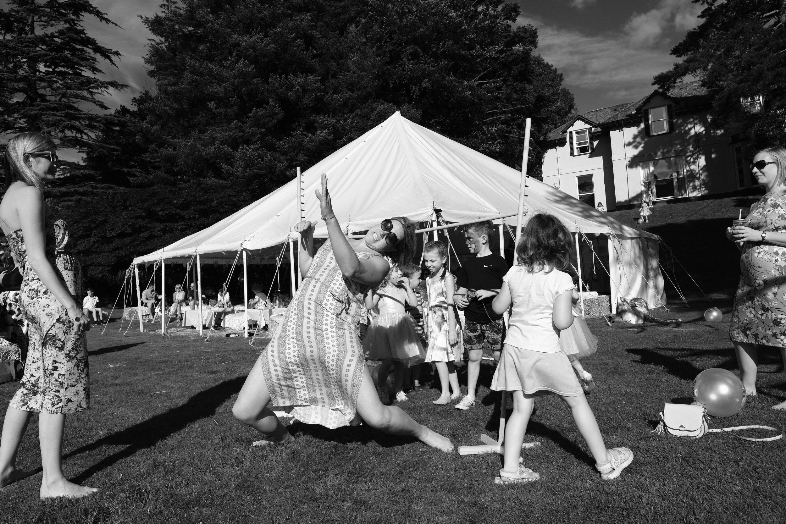 A black and white photo of a guest limbo dancing at Julia and Darren's Lake District wedding by Barry Forshaw
