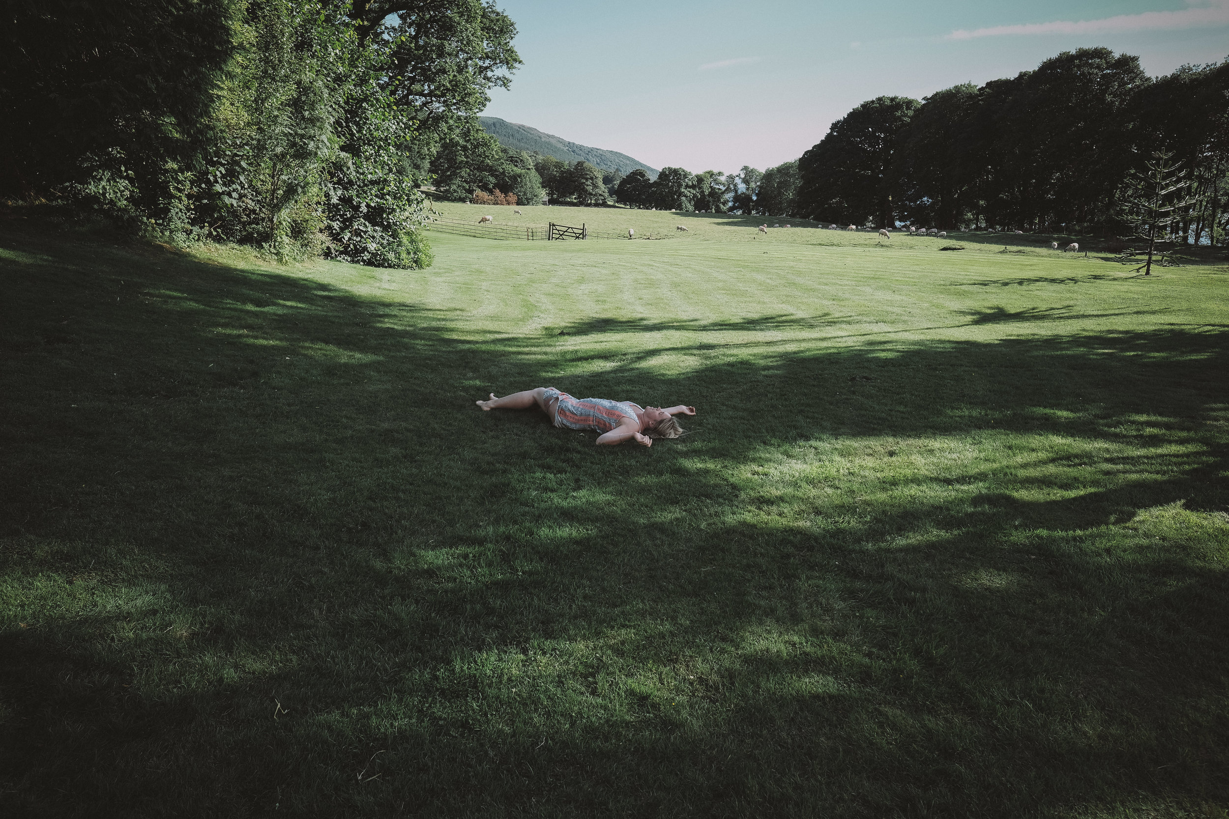 A wedding guest lies on the ground exhausted at Julia and Darren's Lake District wedding by Barry Forshaw
