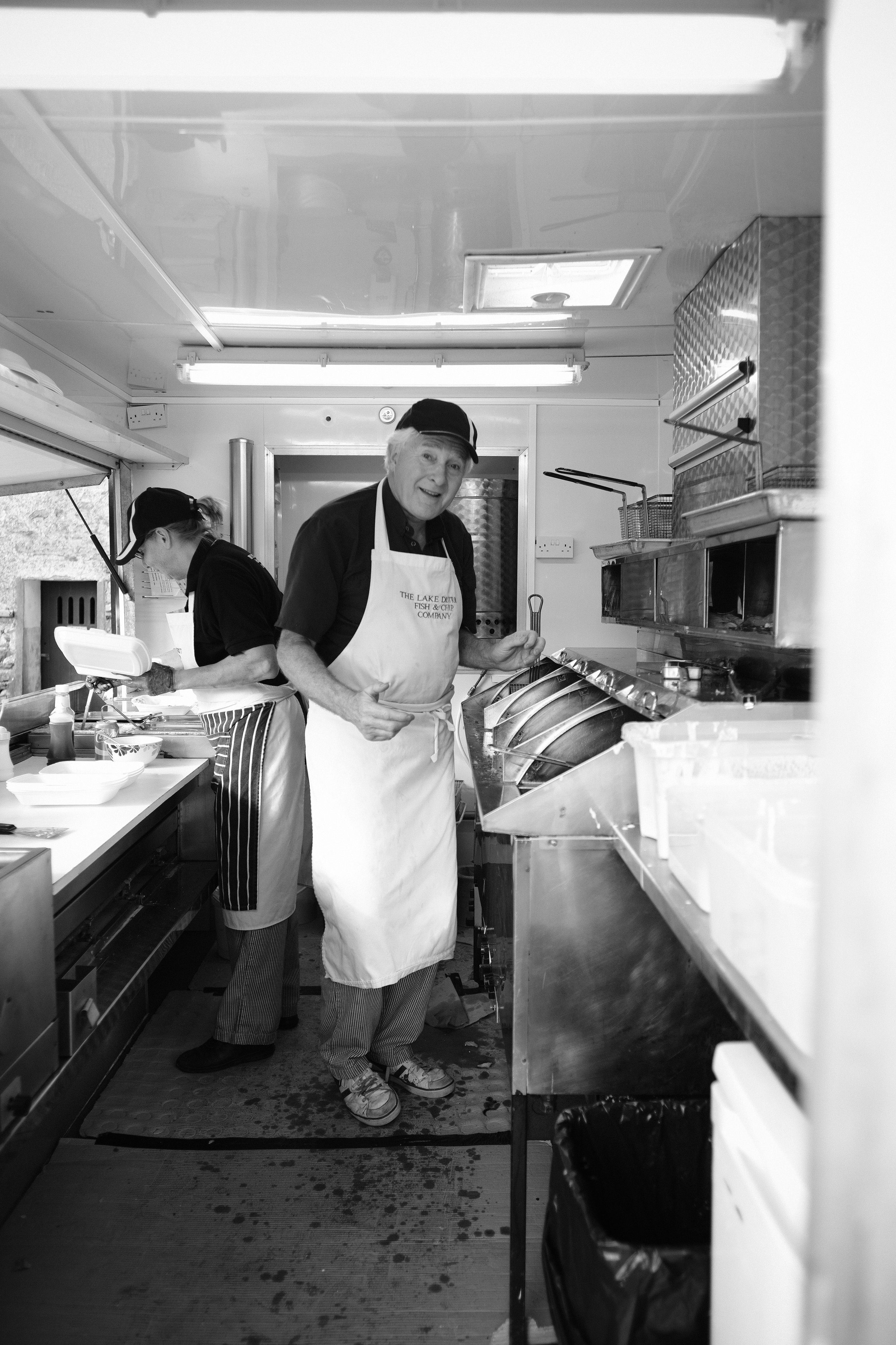 A black and white photo of wedding guests are served fish and chips