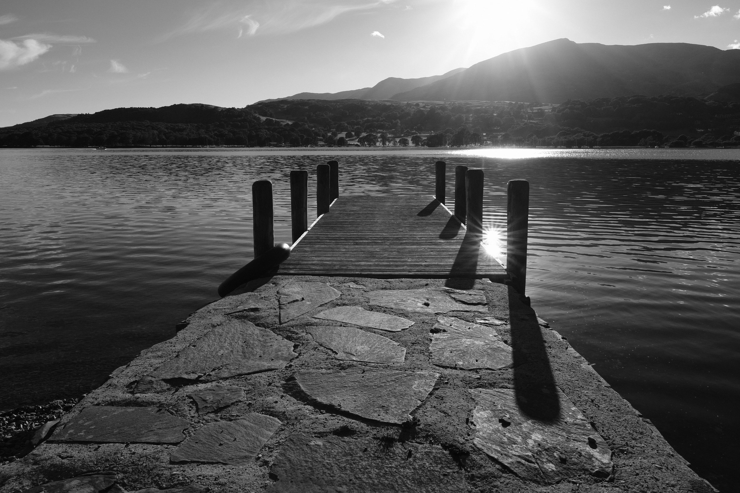 A black and white photo of a jetty on Coniston Water at Julia and Darren's Lake District wedding by Barry Forshaw