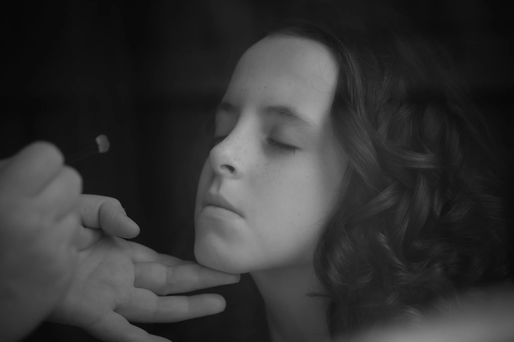 Black and white portrait of flower girl having her makeup applied