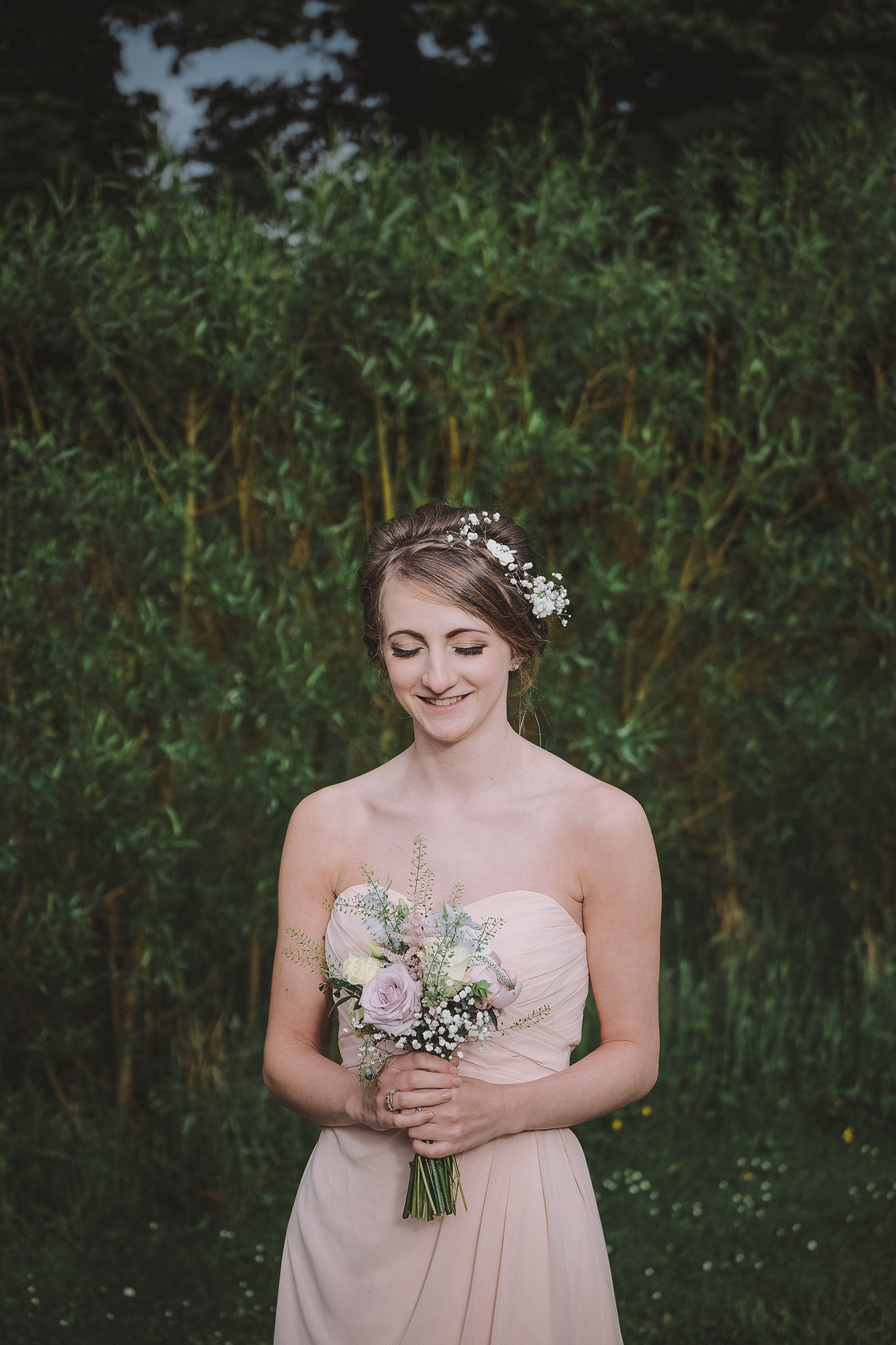 Portrait of bridemaid with eyes shut in the grounds of Newton Hall, Northumberland