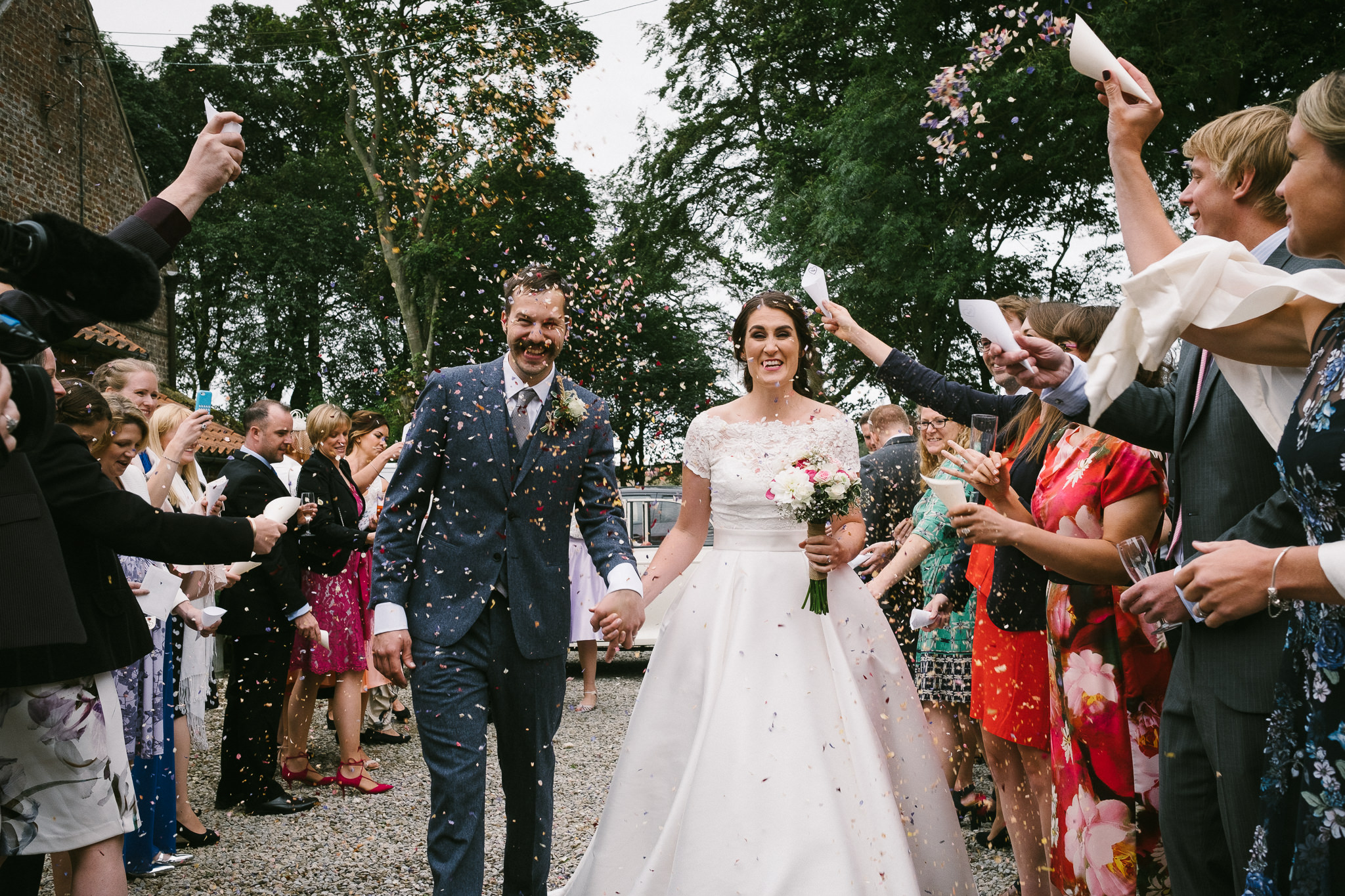 Colourful photo of the bride and groom being showered in confetti