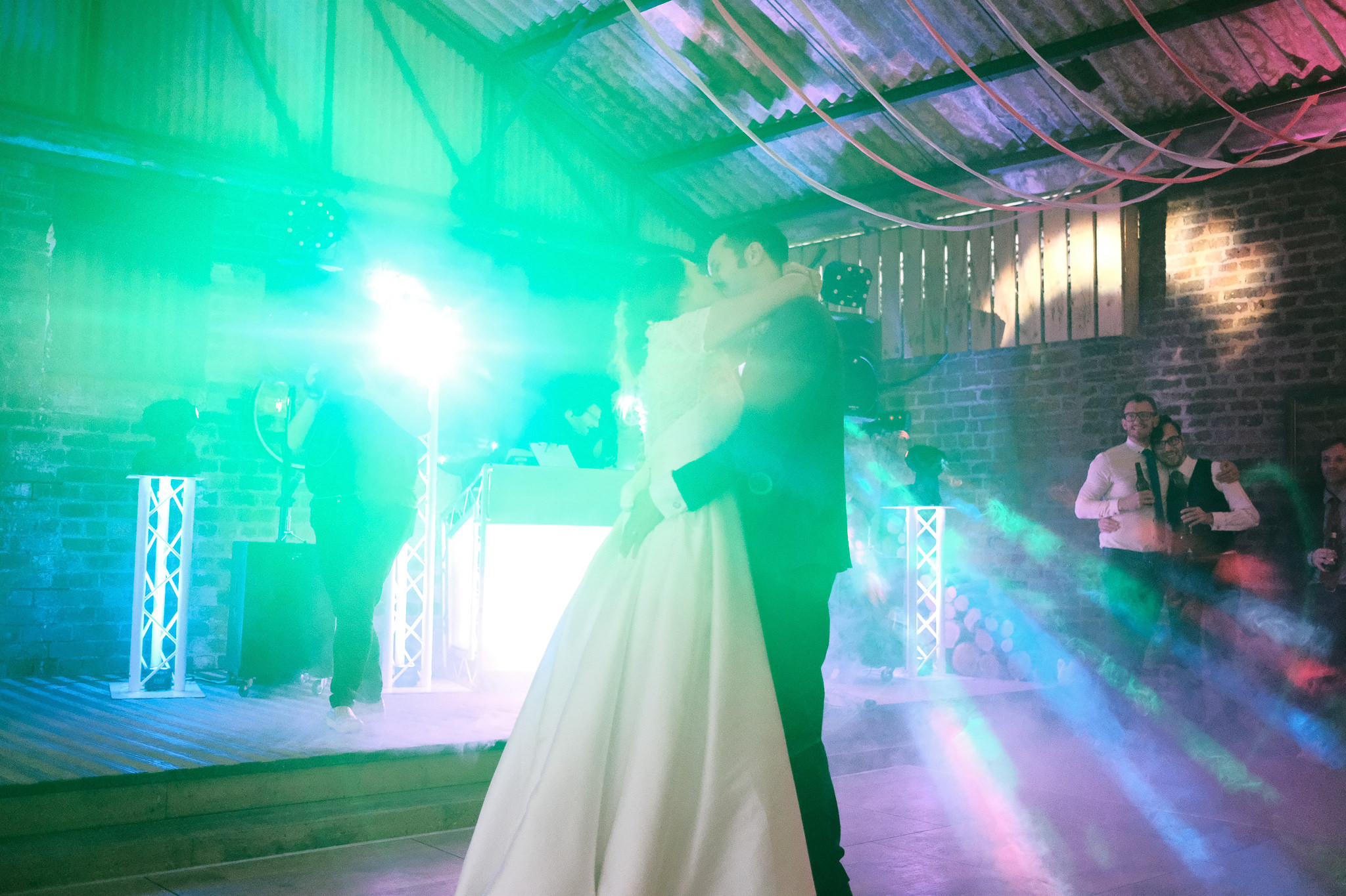 Bride and groom dance under disco lights while same sex couple cuddle in background