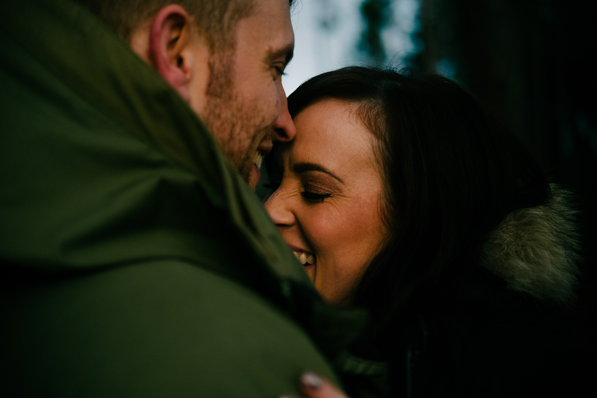 Close up of engaged couple laughing in Kielder Forest