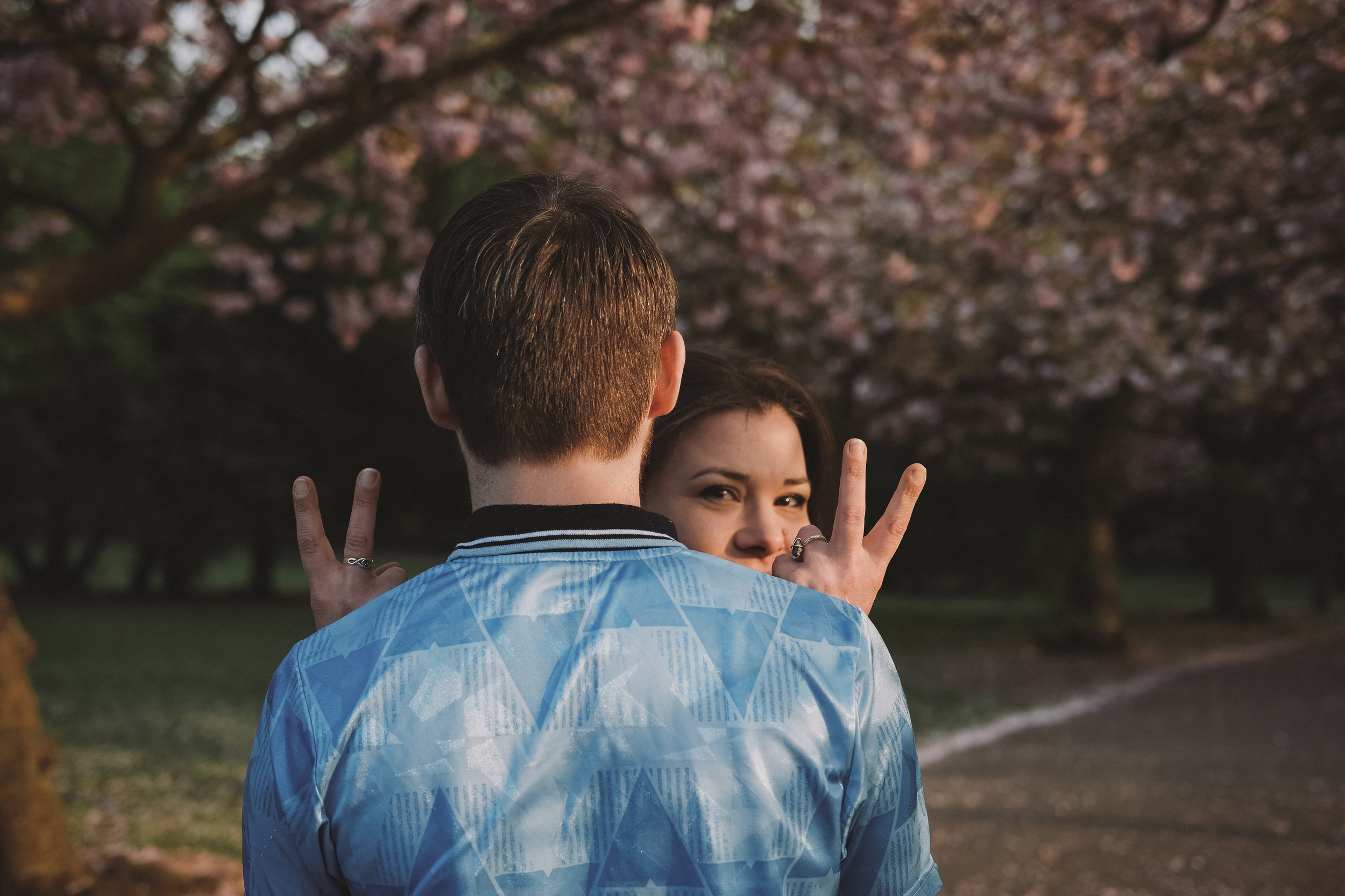 Girl flicks v's over guy's shoulder on pre-wedding shoot in Saltwell Park