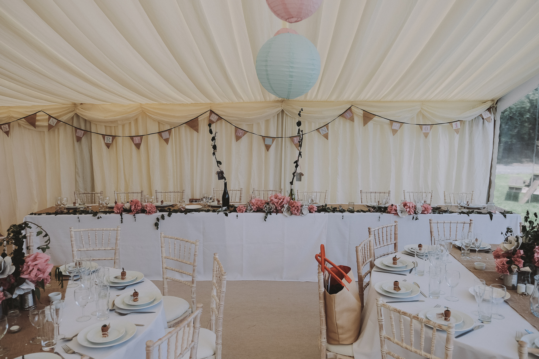 The top table in a marquee showing a long line of homemade paper flowers