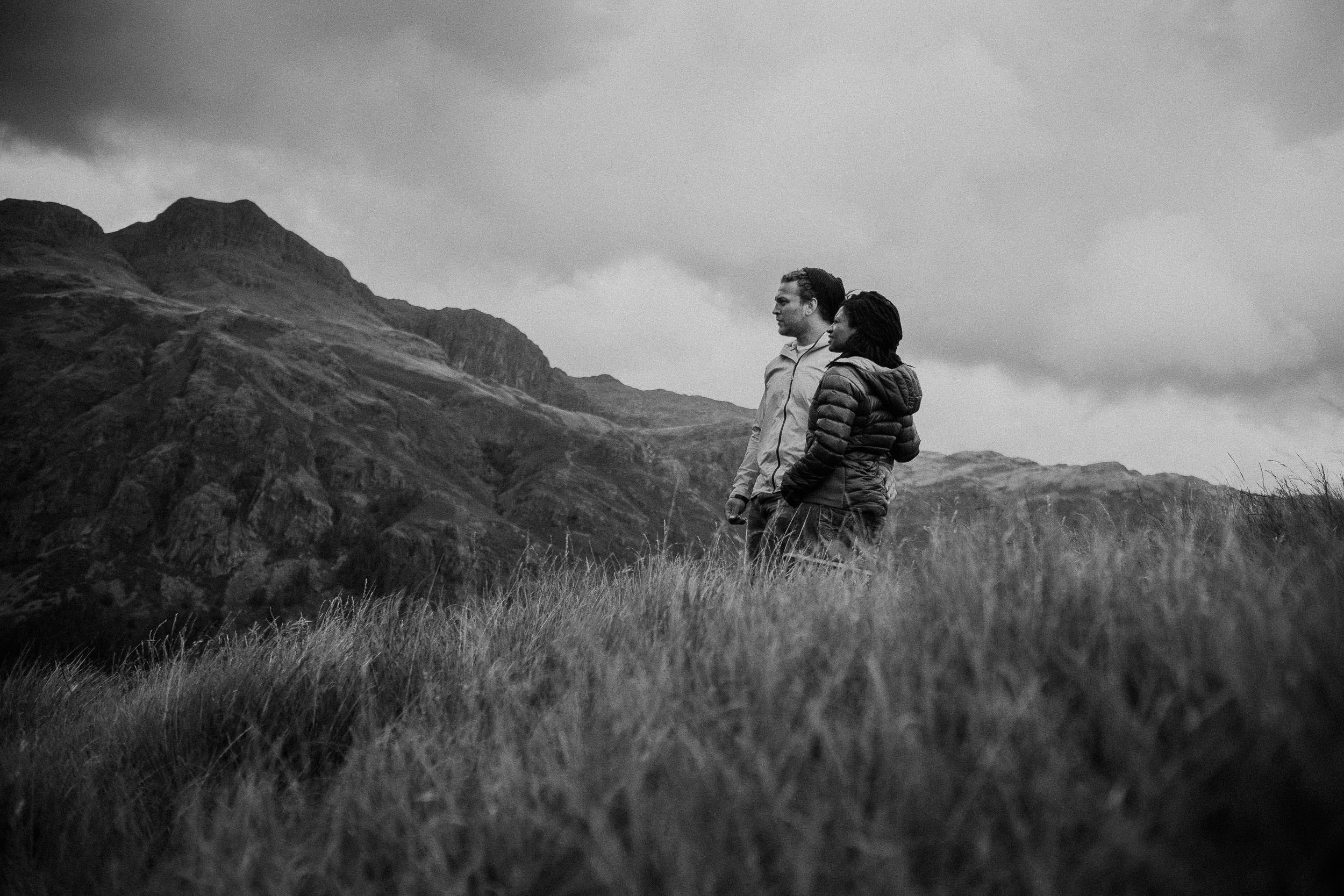 Black and white photo of couple cuddling while looking out over Lake District scenery