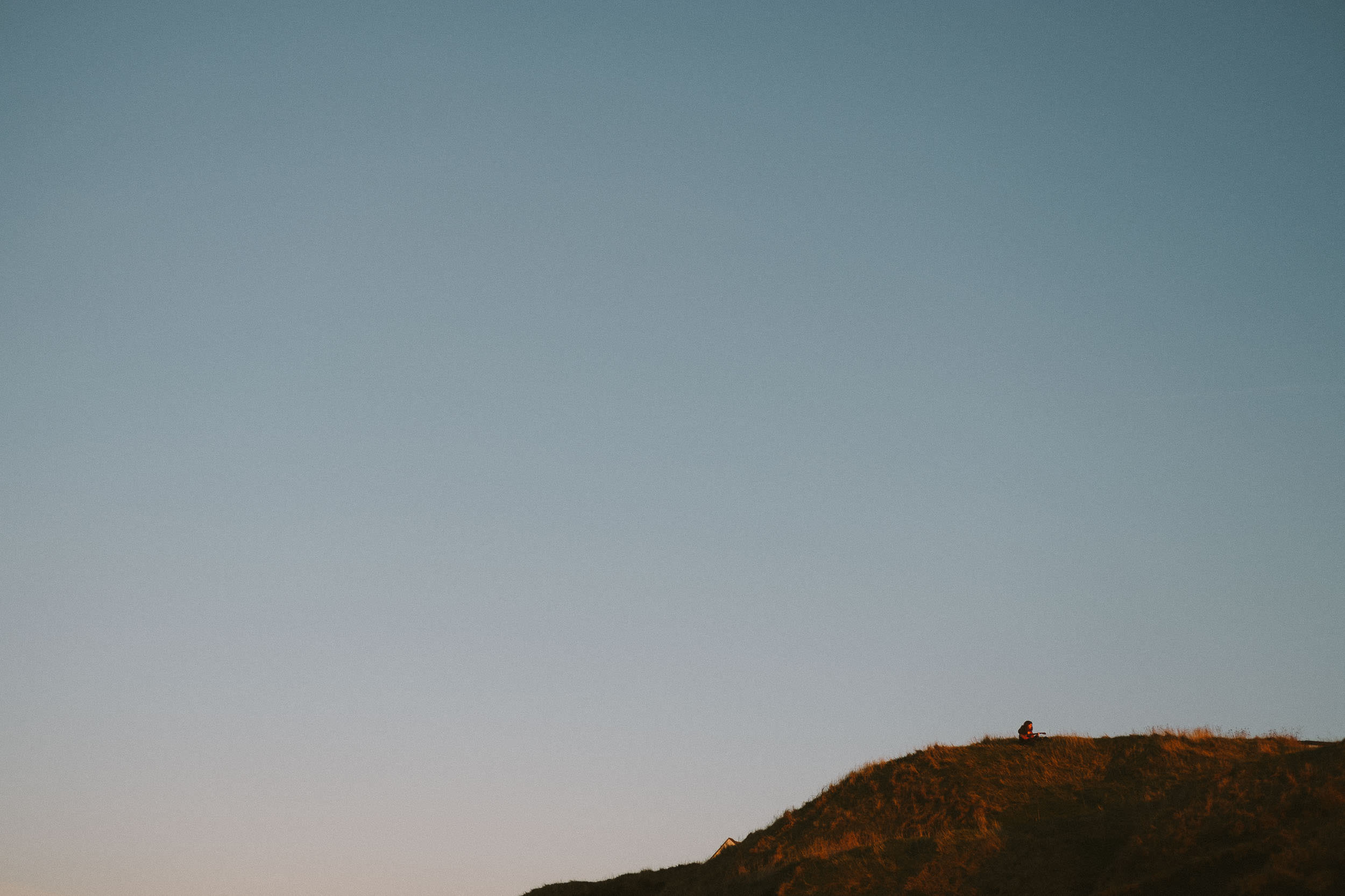 Girl playing guitar on clifftop on Northumberland coast
