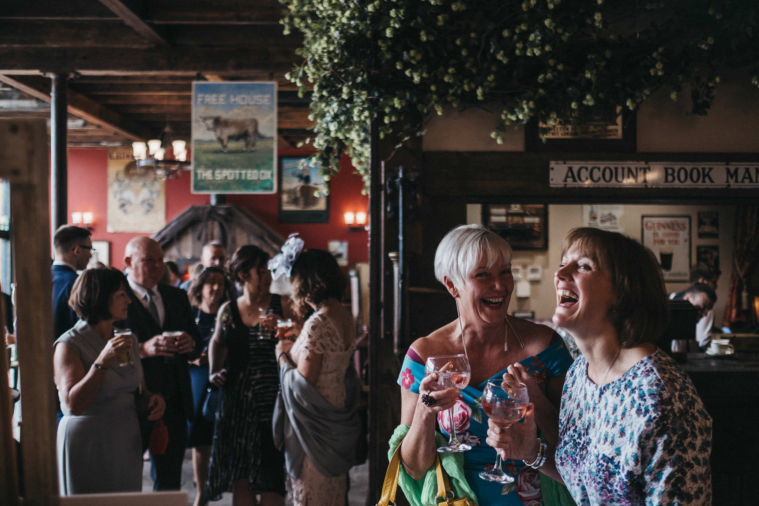 Two guests roar with laughter at wedding