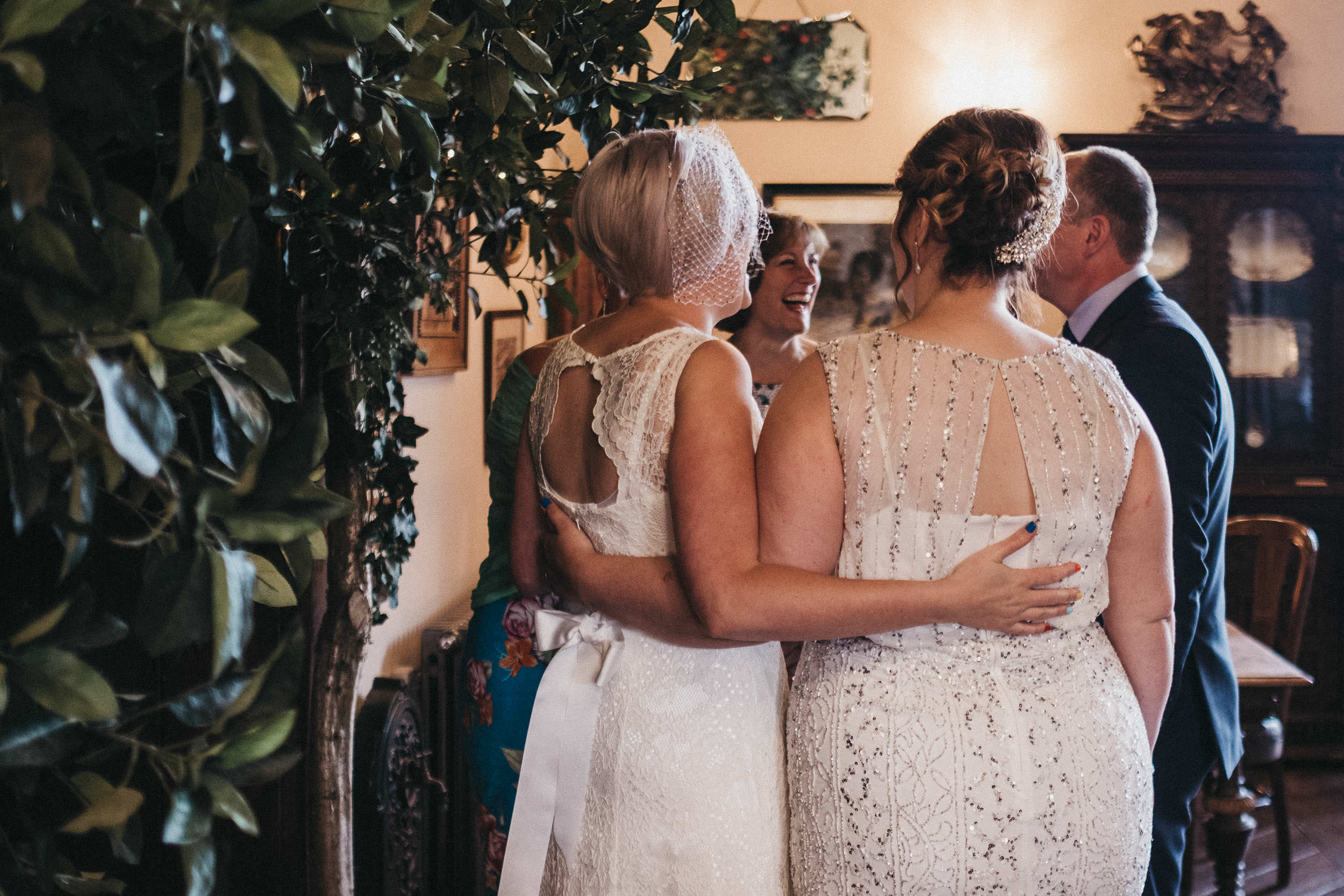 Brides hold each others backs during wedding reception