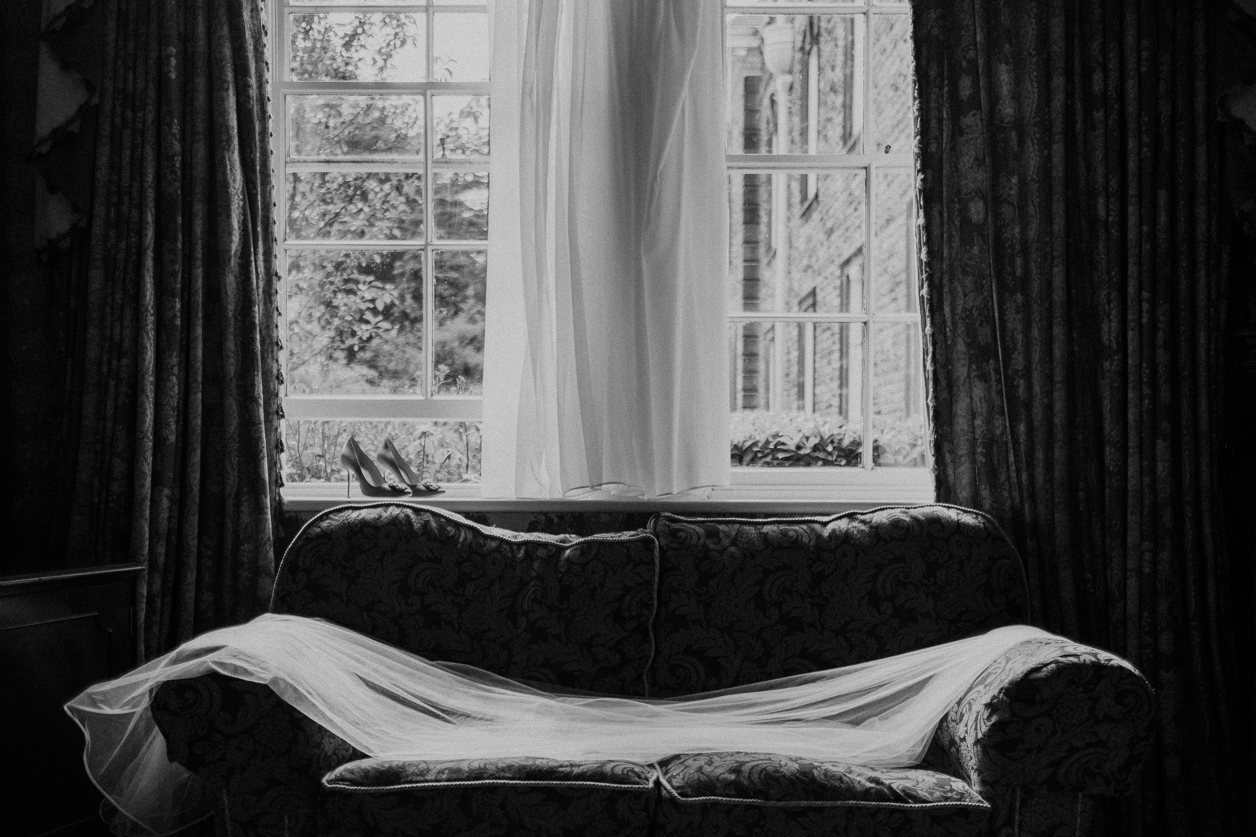 Black and white photo of dress, veil and wedding shoes