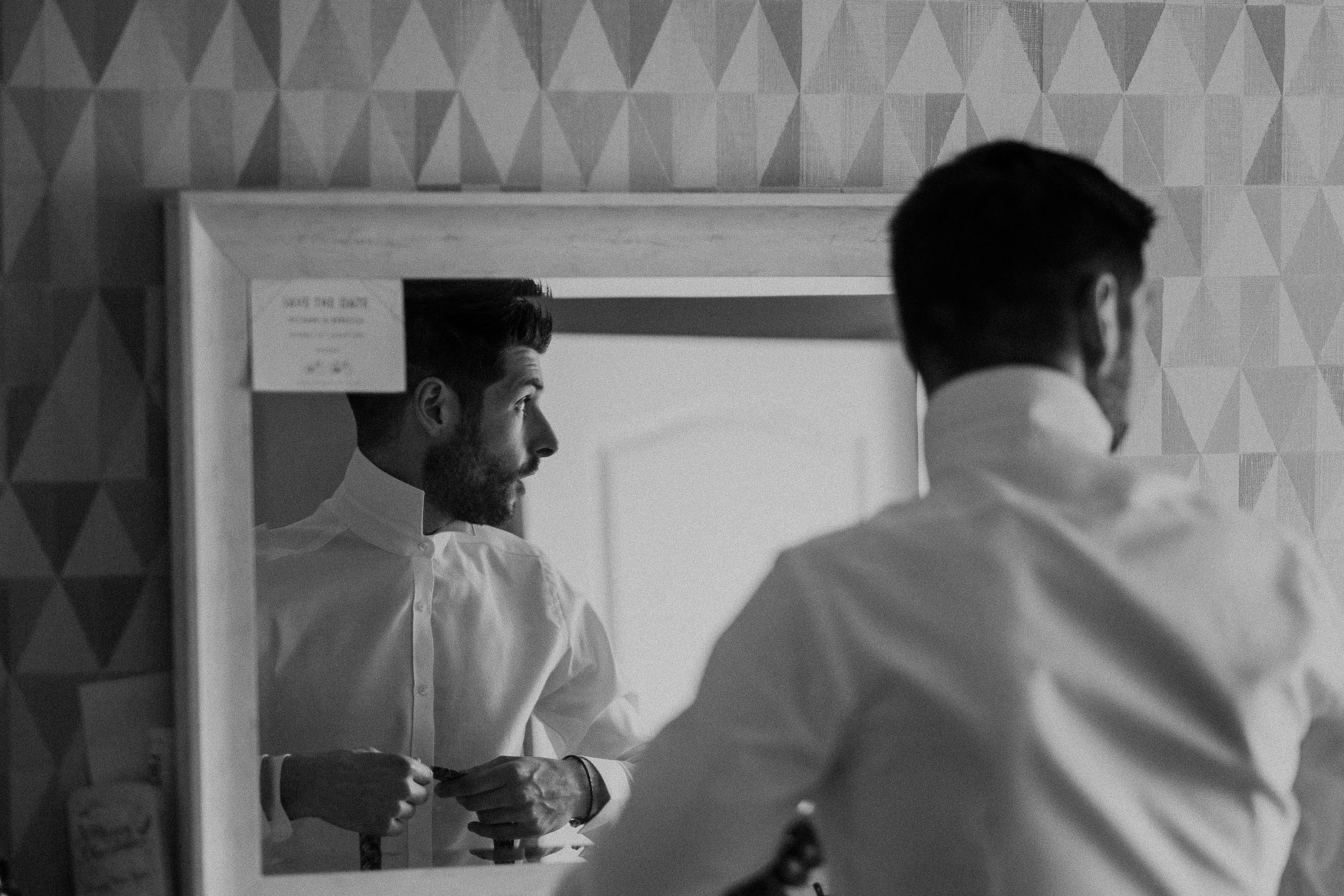 Black and white photo of groom reflected in mirror