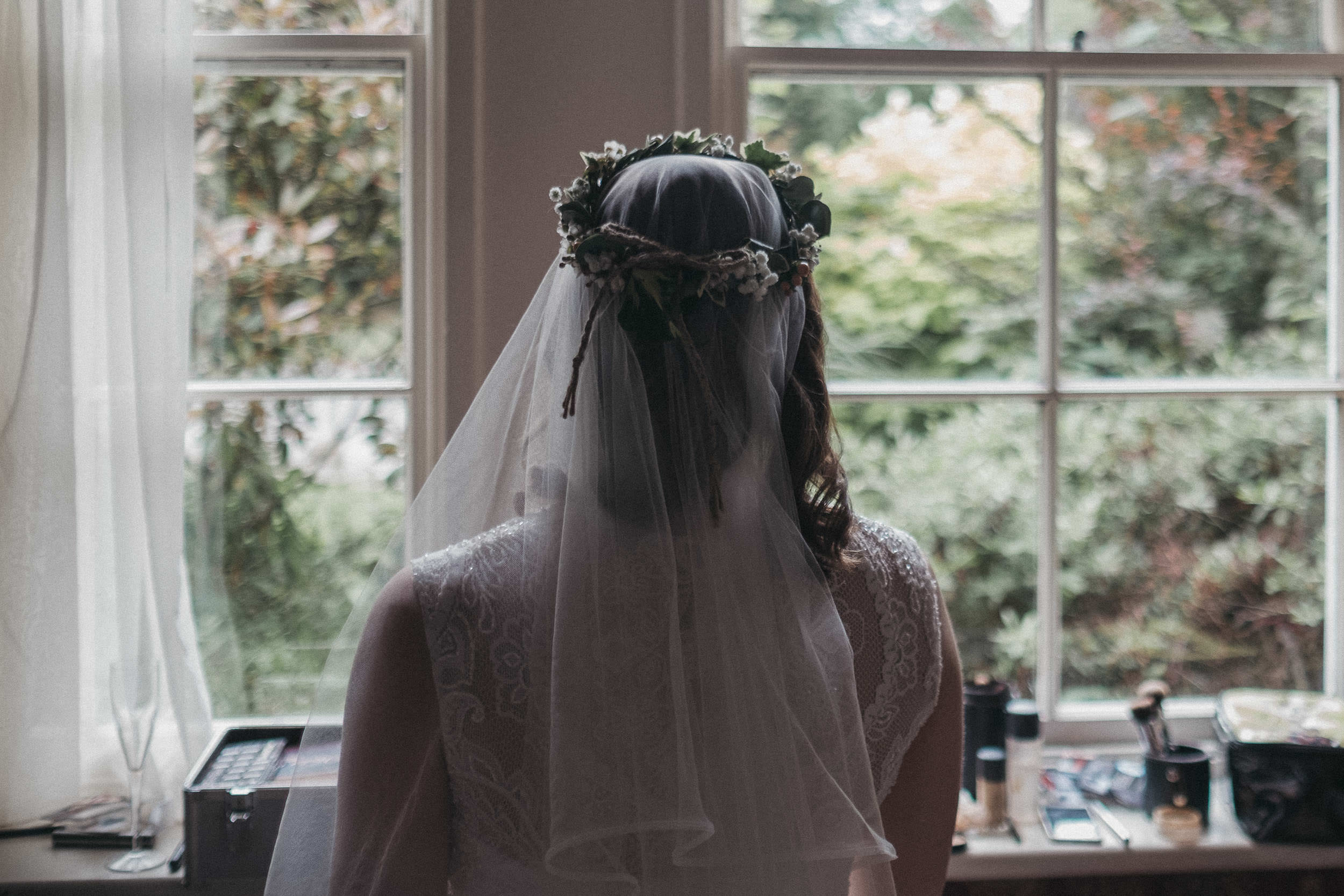Bride with flower crown looking out of window
