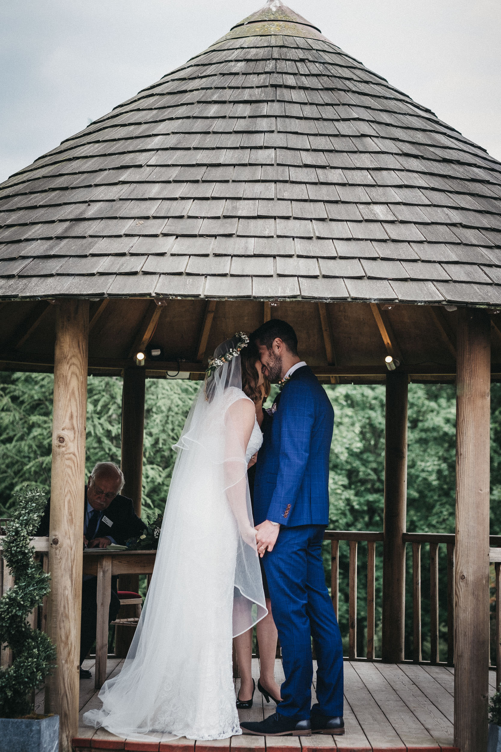 Bride and groom kiss in gazebo during wedding ceremony