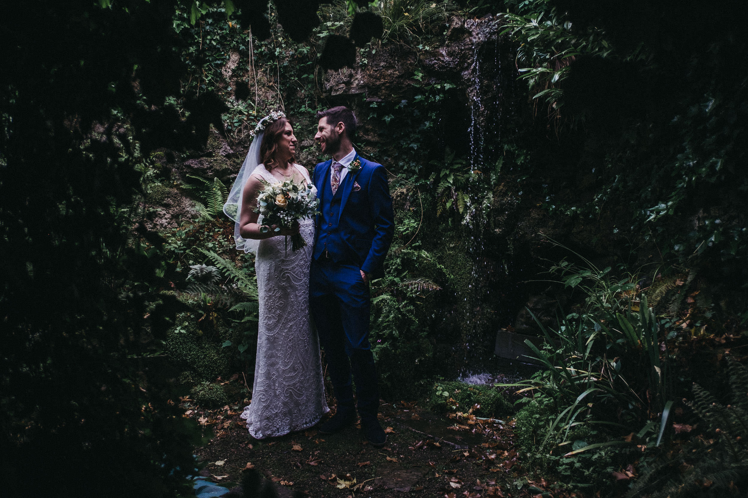 Moody photo of bride and groom with waterfall