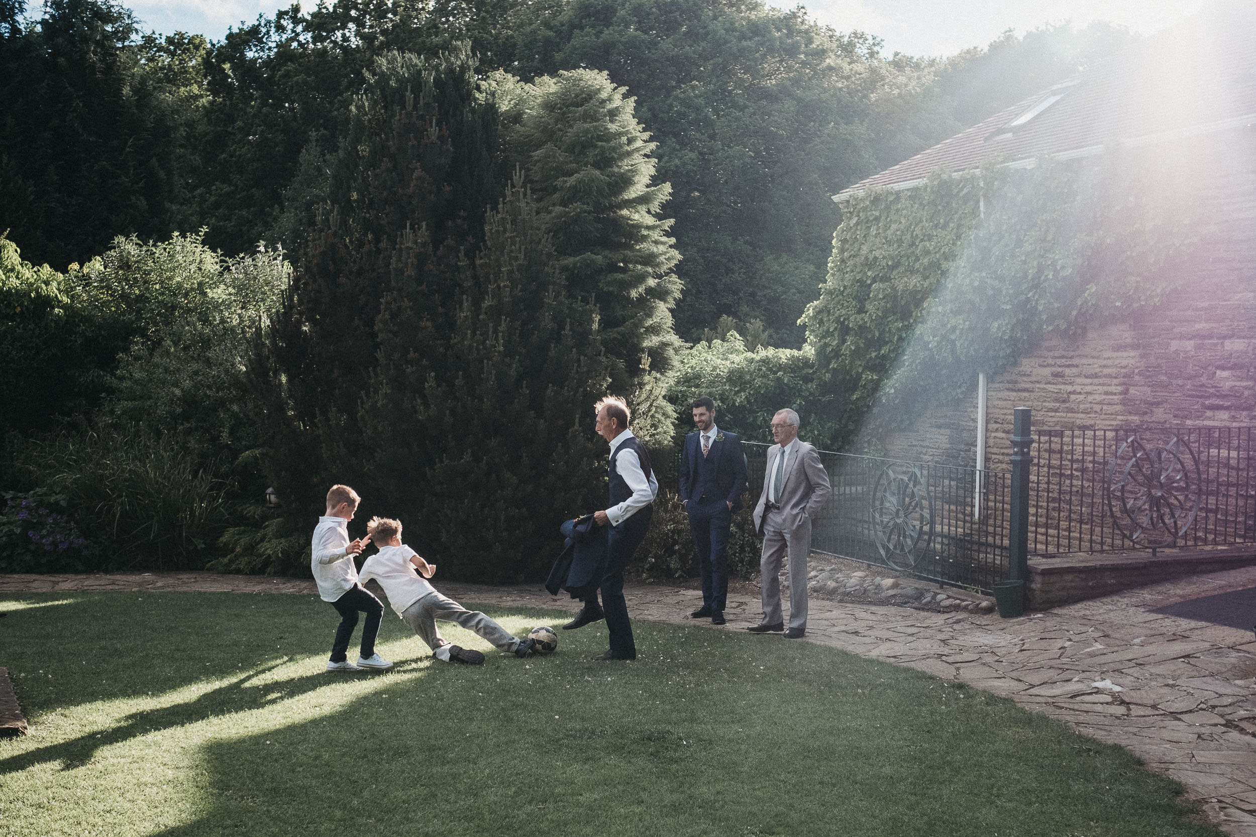 Wedding guests play football in blazing sunlight