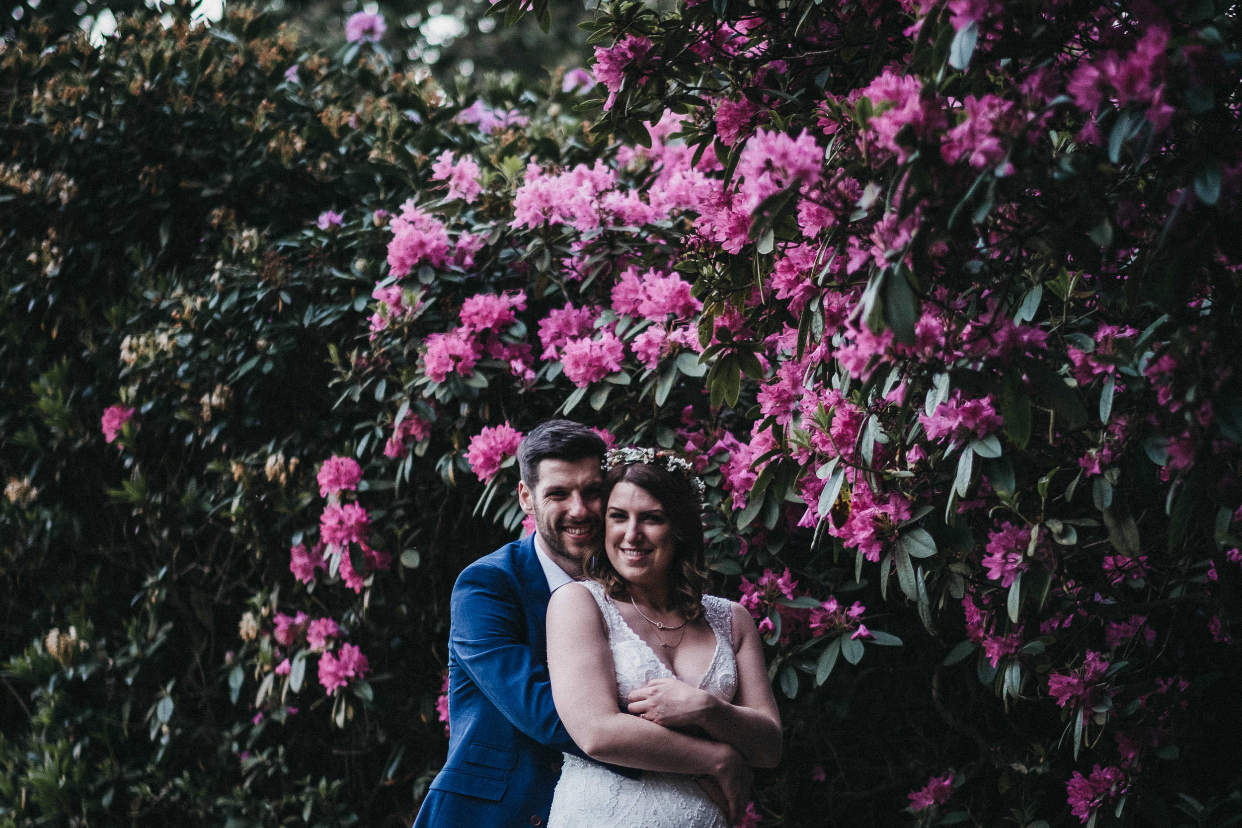 Bride and groom hug with wall of pink flowers all around