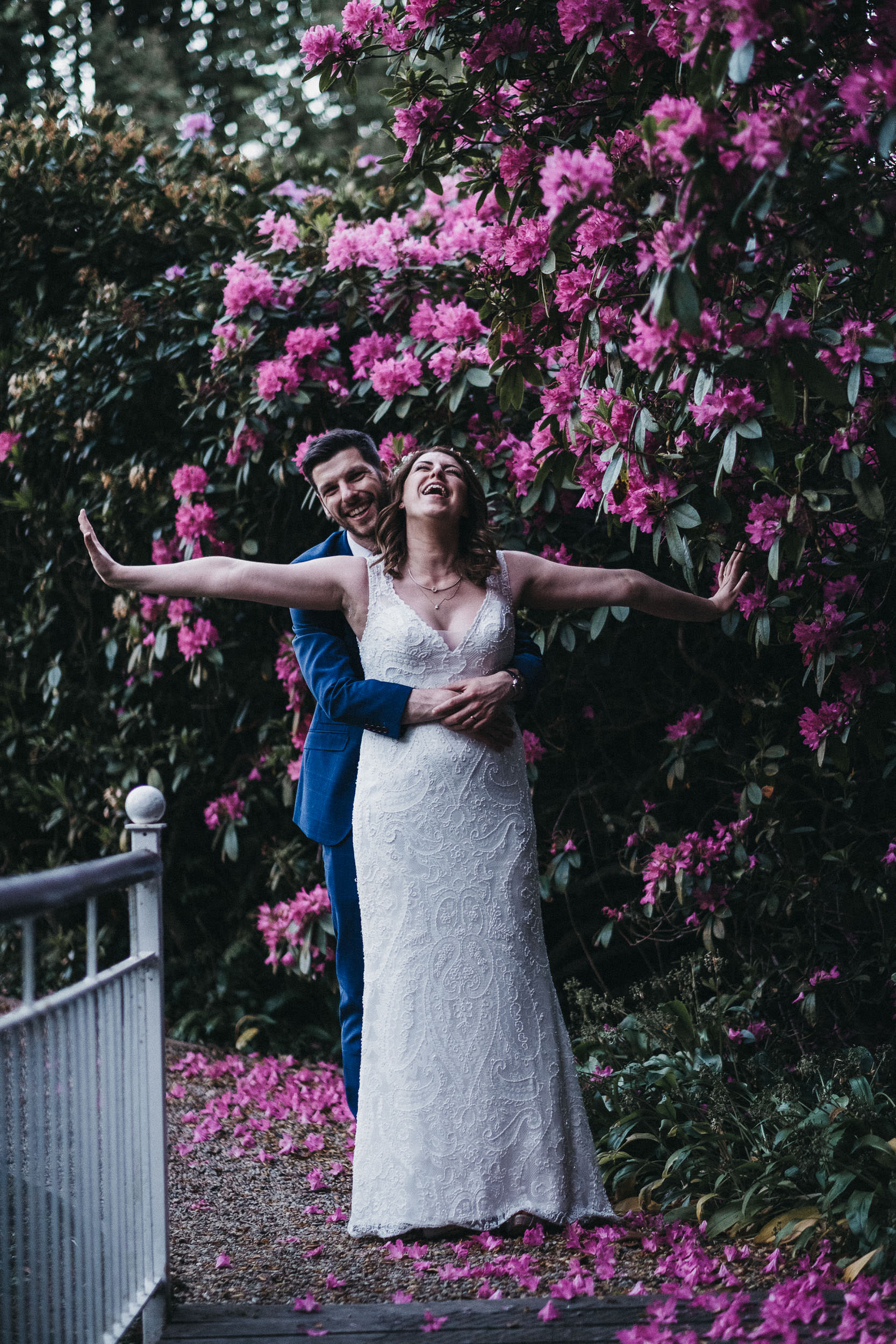 Bride and groom laughing with pink flowers in background