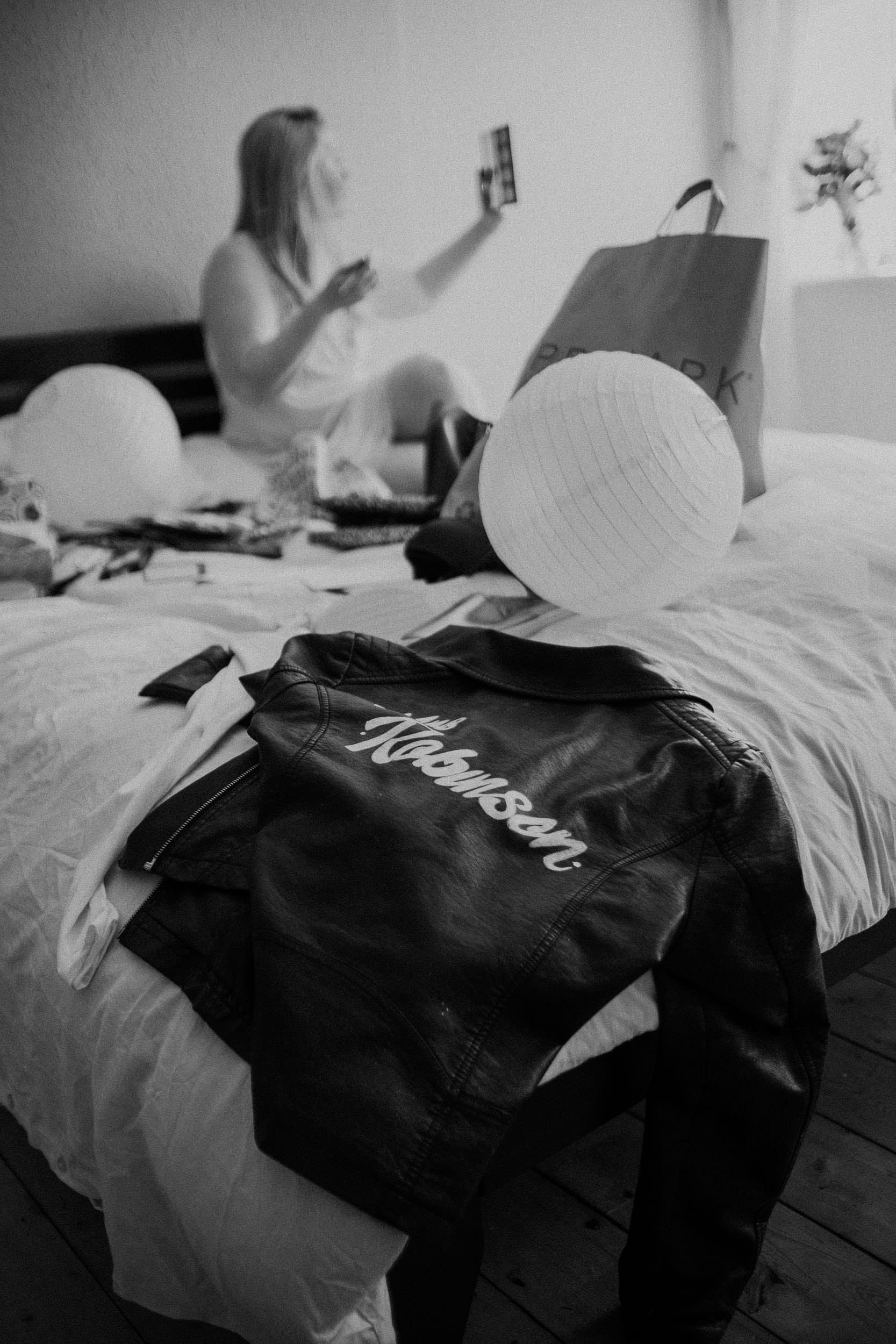 Black and white photo of bride's leather jacket with bride getting ready behind
